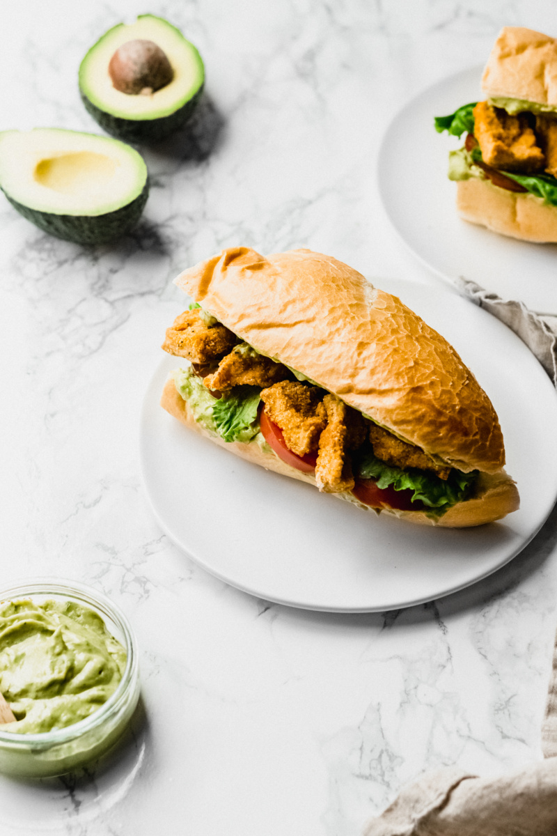 overhead view of a tofu po boy sandwich with avocados on the side