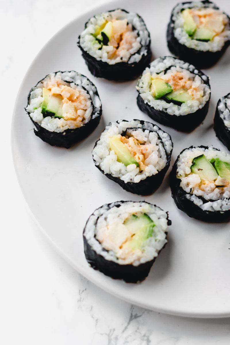 a plate of vegan California roll slices, filled with avocado, cucumber and hearts of palm