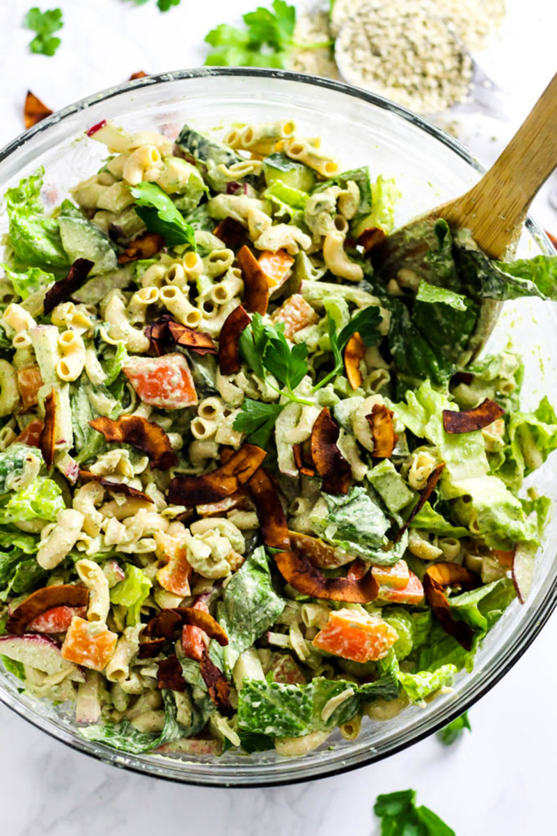 a vegan ranch pasta salad with macaroni noodles, olives, lettuce, tomatoes and coconut bacon