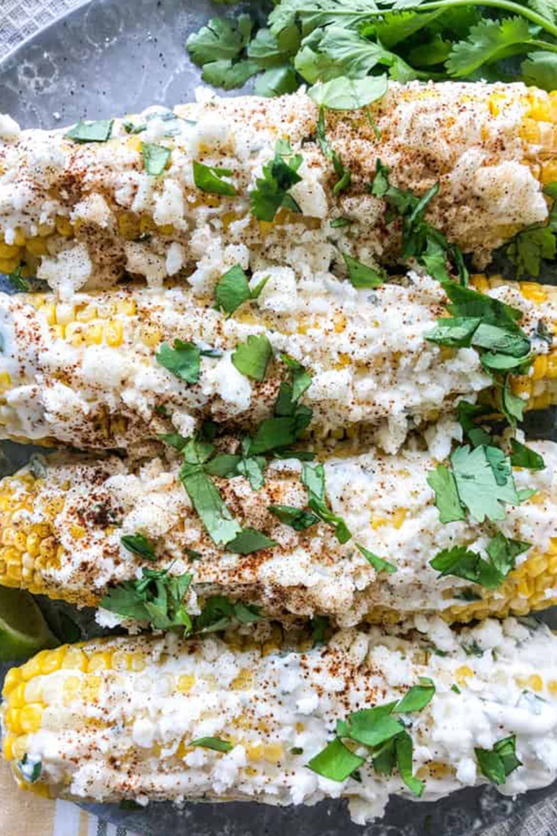 Four Mexican street corn cobs topped with chopped cilantro 