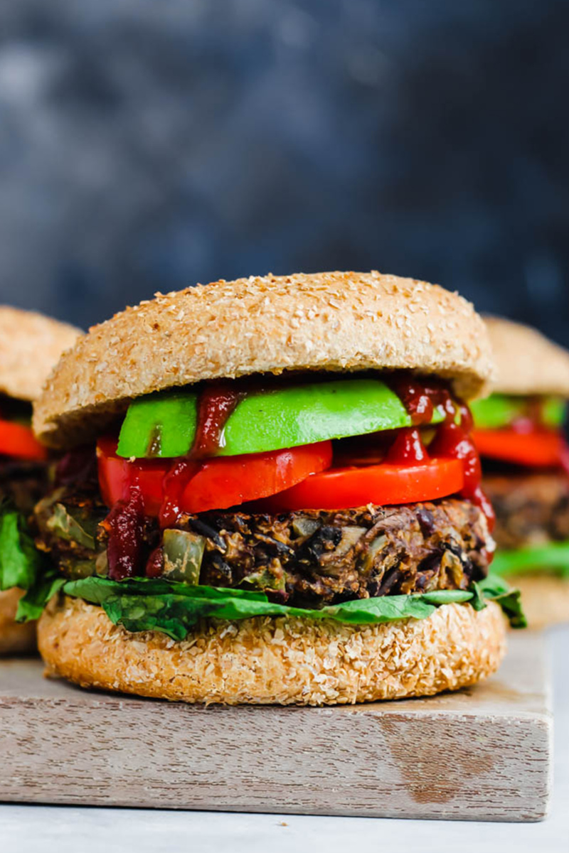 a smoky wild rice mushroom and black bean burger topped with tomatoes lettuce and ketchup
