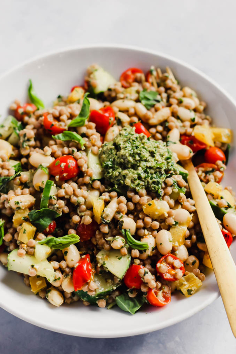 vegan pesto couscous salad with tomatoes, sliced vegetables and a dollop of pesto