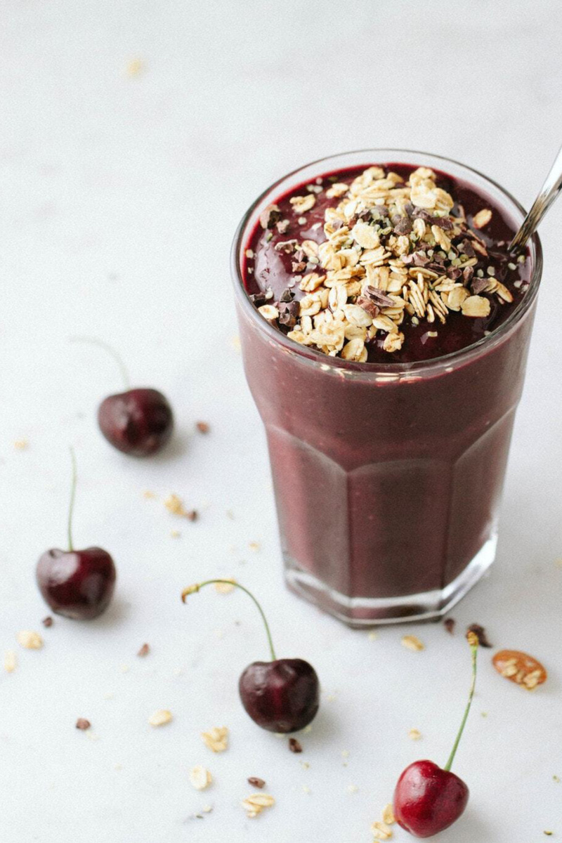 a glass of chocolate cherry smoothie topped with oats