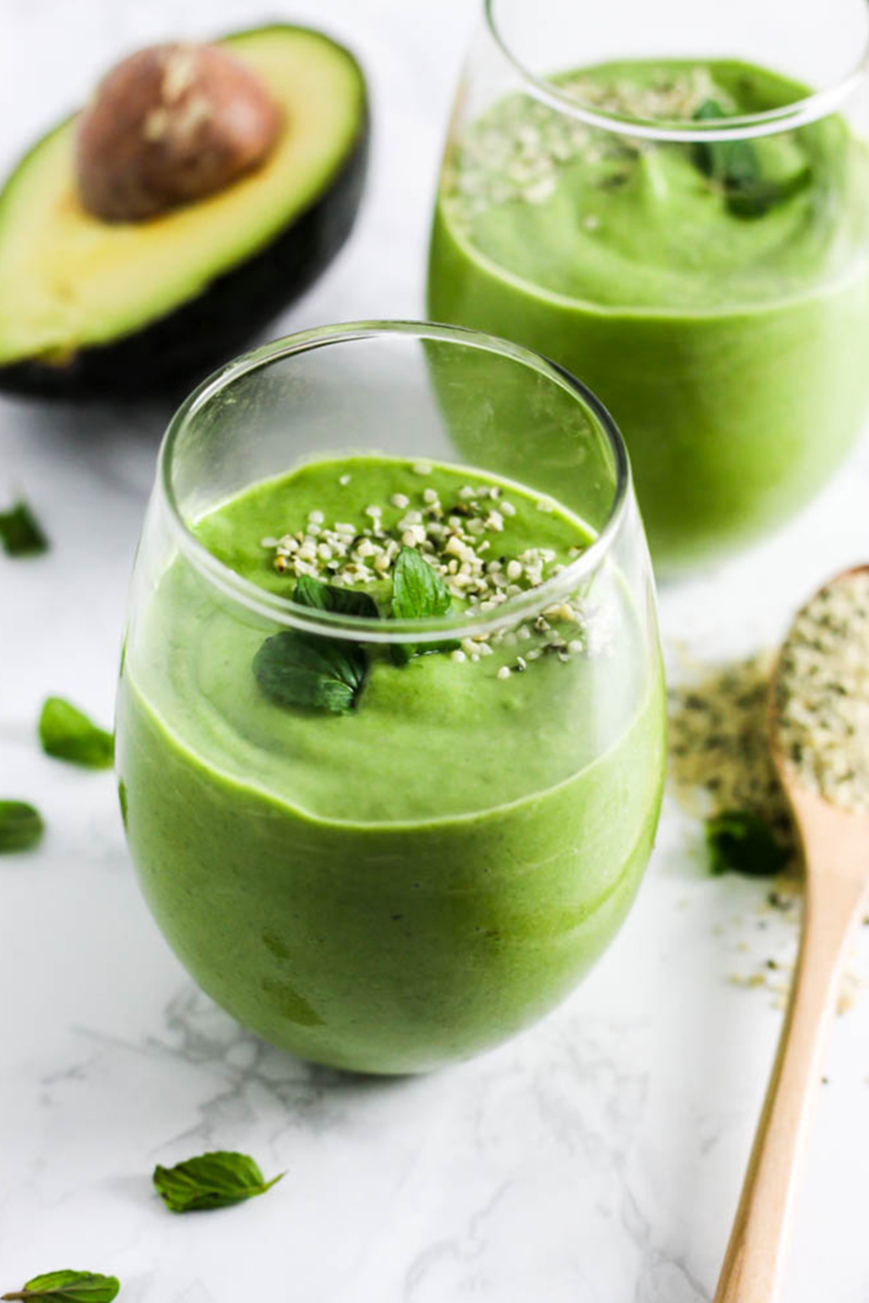 two cups of green smoothie topped with mint and hemp seeds