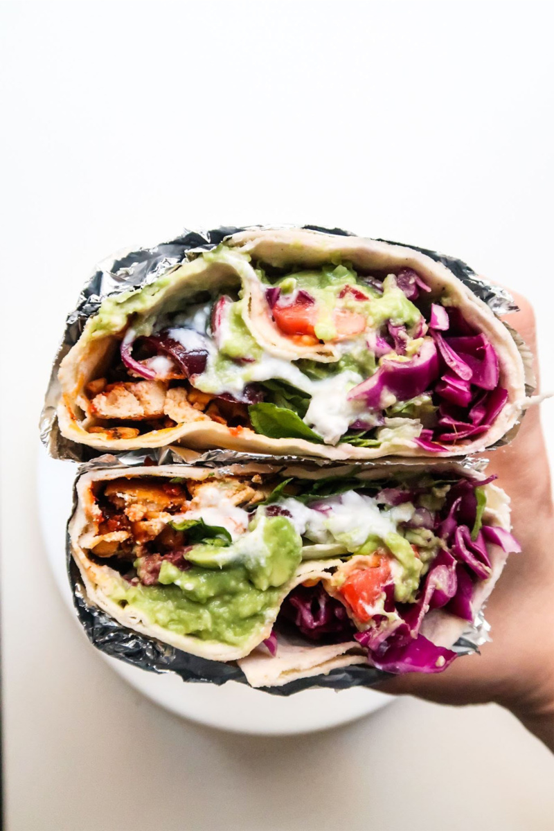 a hand holding two halves of a veggie wrap