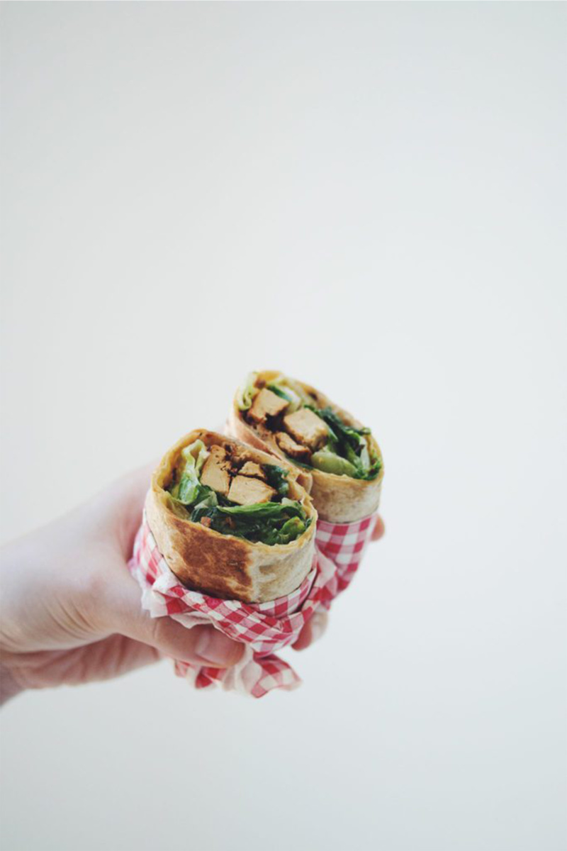 a hand holding a tofu caesar wrap