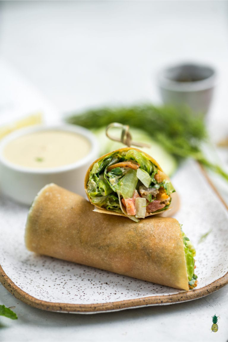 a mushroom caesar wrap cut in half and served with a side of vegan caesar dressing