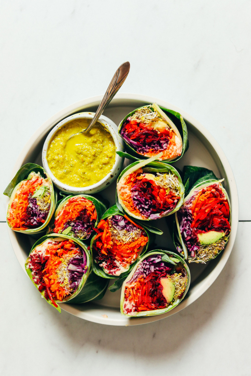 a plate of rainbow wraps filled with veggies and served with a curry sauce