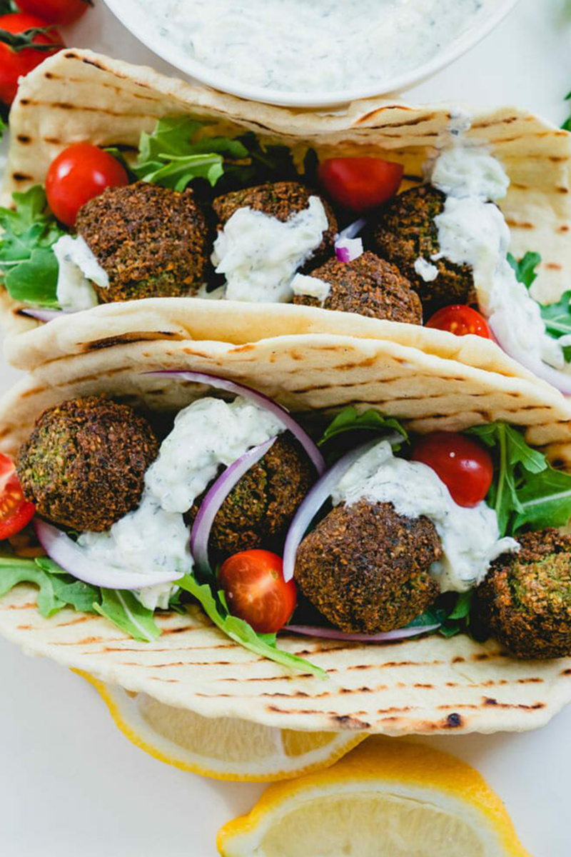 two falafel sandwiches topped with dairy free tzatziki