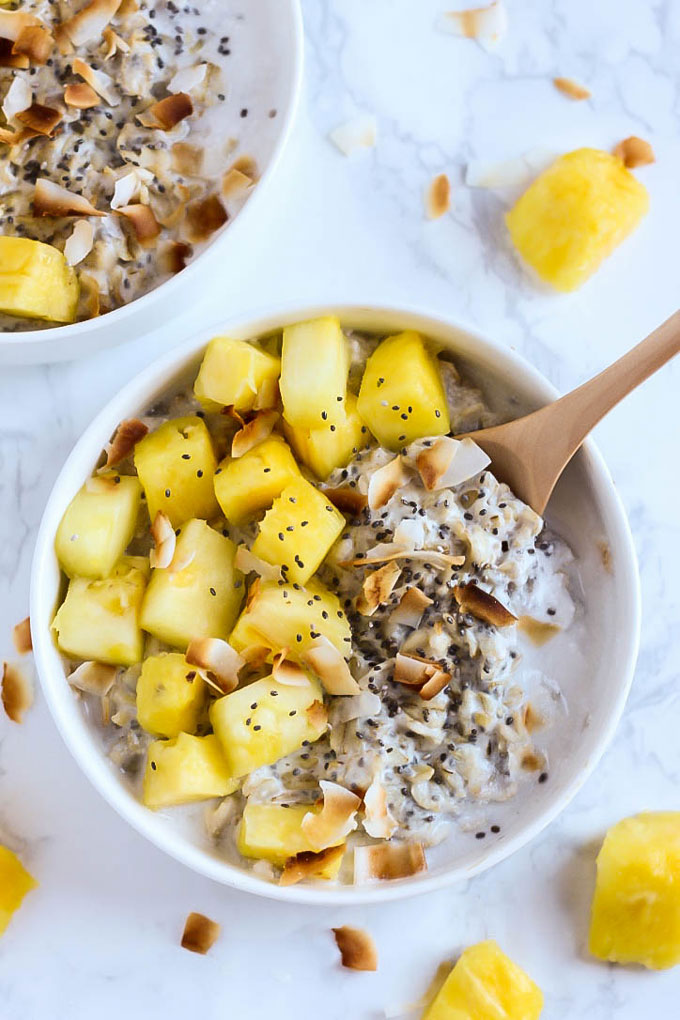 a bowl of overnight oats topped with toasted coconut and pineapple