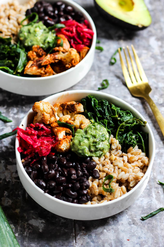 a power bowl filled with brown rice, black beans, cabbage, cauliflower, greens and avocado pesto