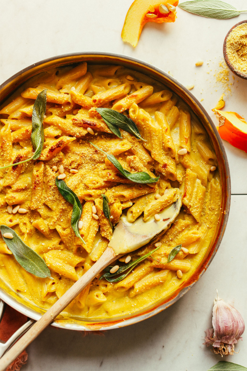 a skillet of vegan mac and cheese topped with fresh sage leaves