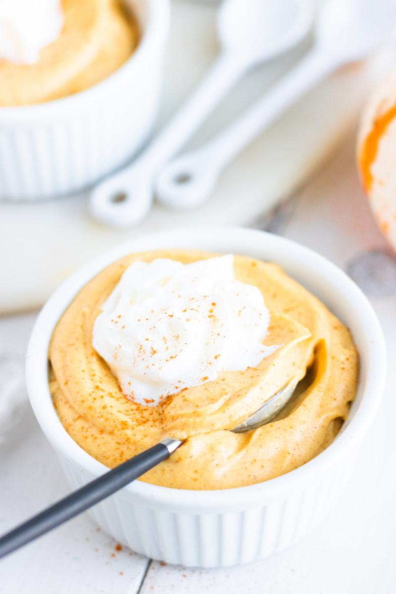a ramekin of homemade pumpkin pudding topped with whipped cream
