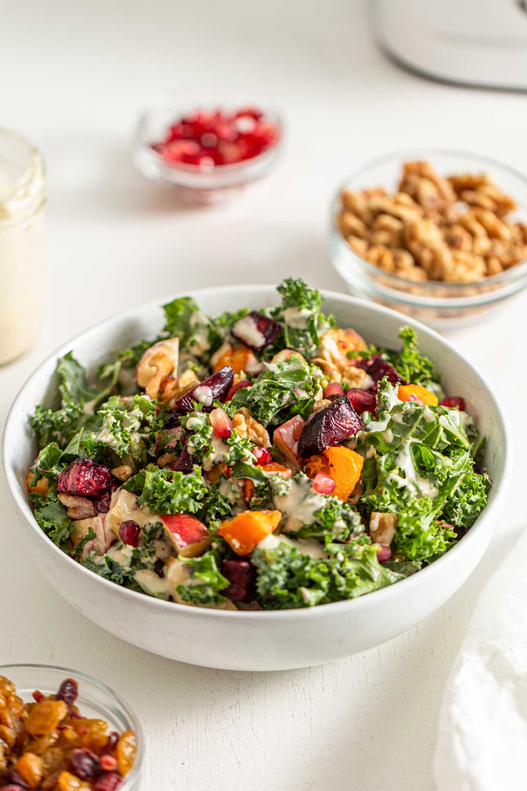 a kale salad topped with apples, squash and a tahini dressing