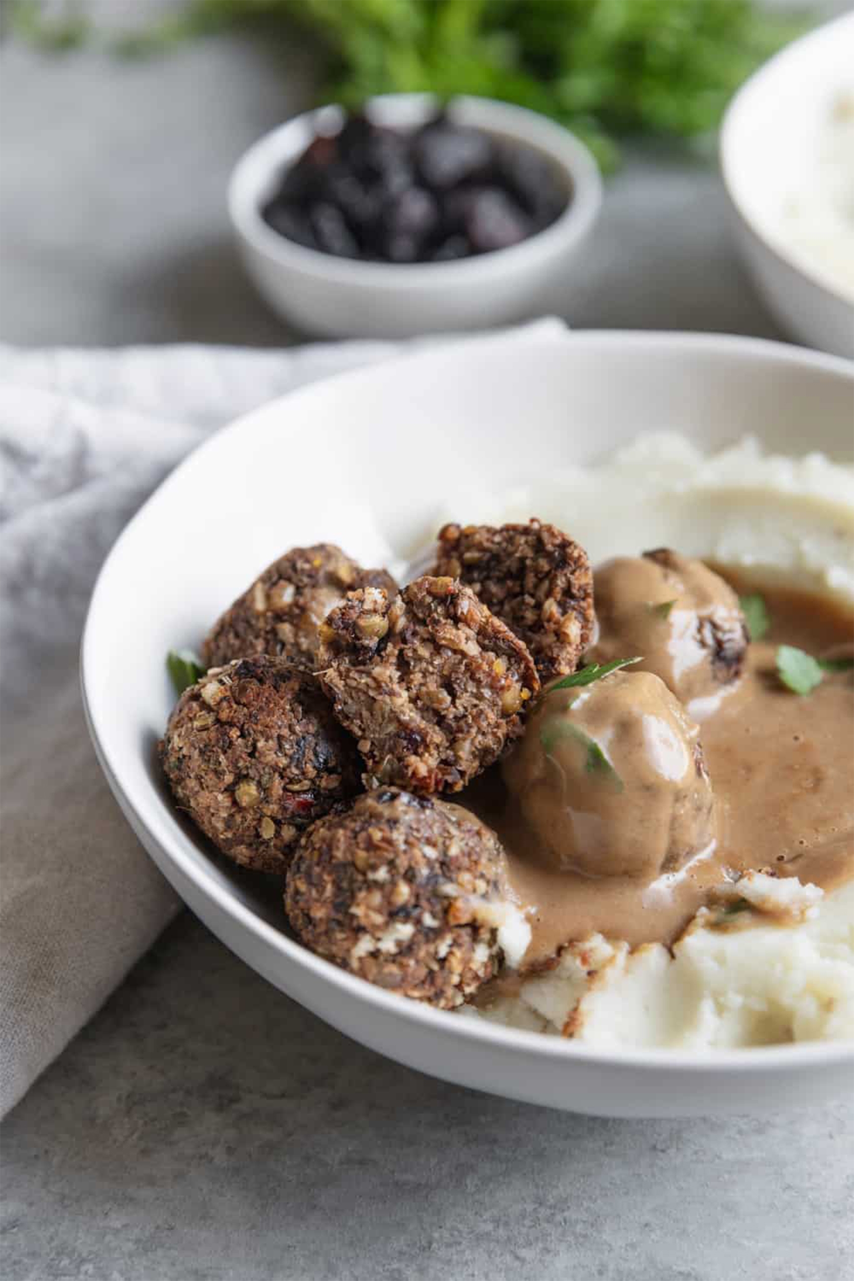a bowl of mashed potatoes topped with gravy and served with vegan meatballs