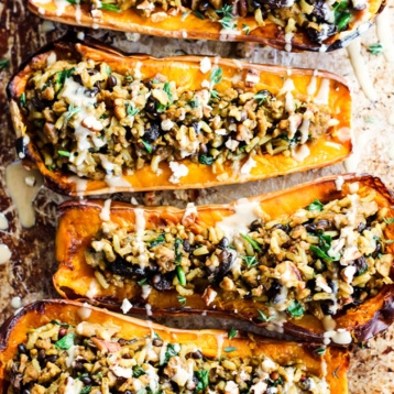 a sheet tray of halved butternut squashes stuffed with veggies and vegan sausage