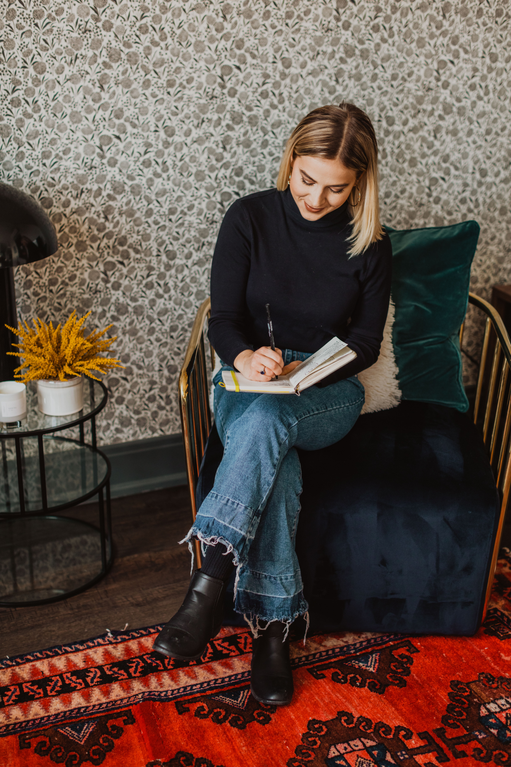 a girl sitting in a chair writing in a notebook