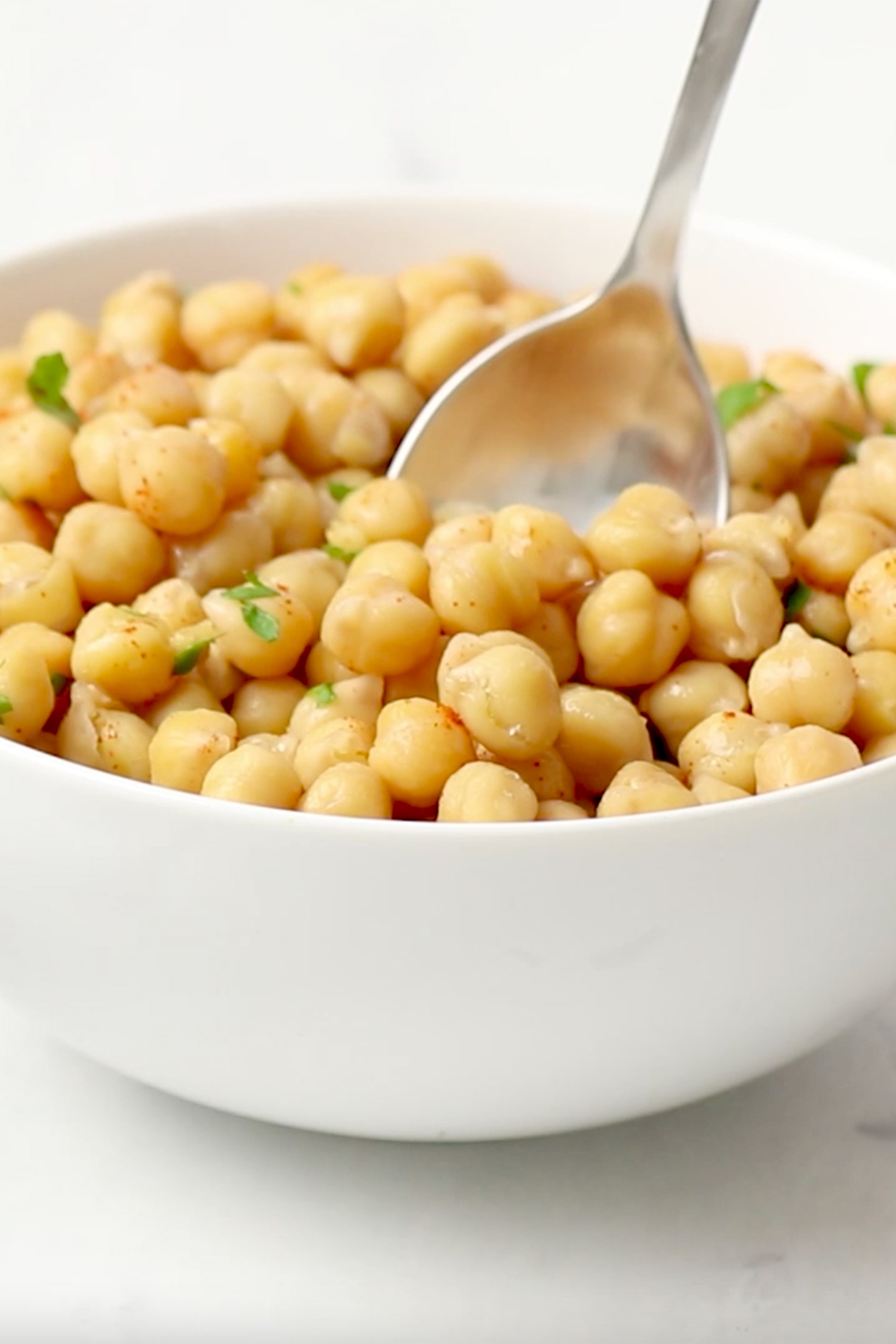 a bowl of cooked chickpeas topped with fresh parsley