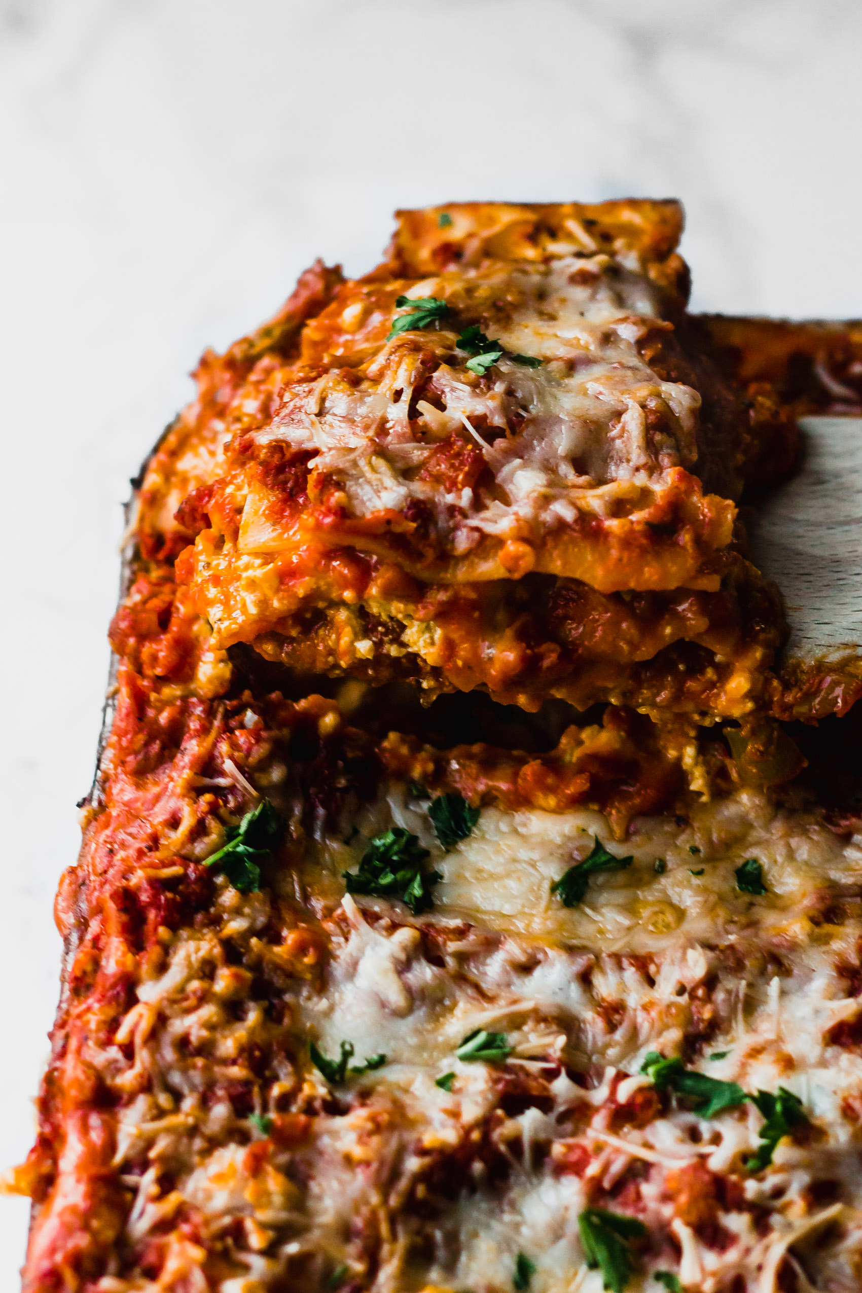 a spatula pulling out a slice from a dish of vegan lasagna