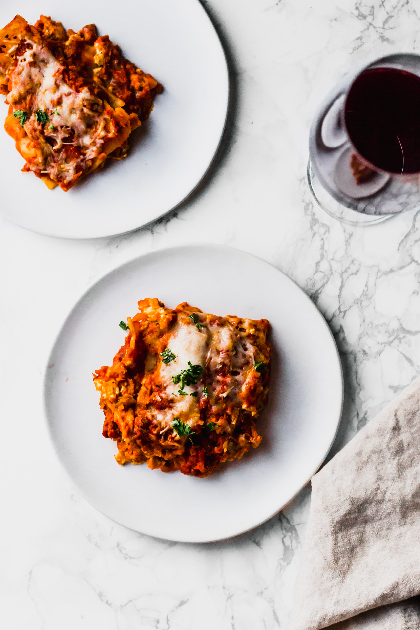 two slices of vegan lasagna served with a glass of red wine