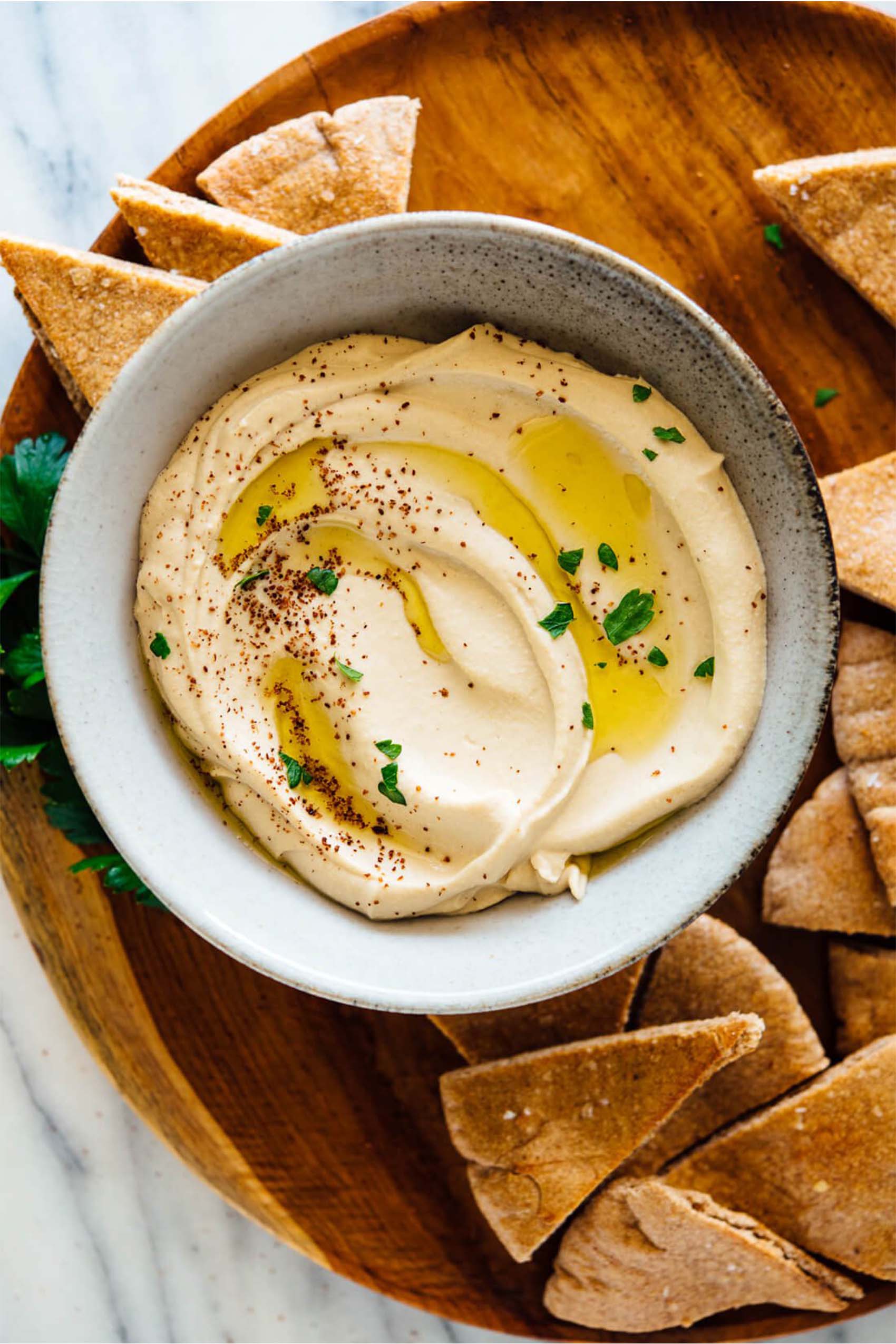 a bowl of homemade hummus topped with olive oil and served with pita