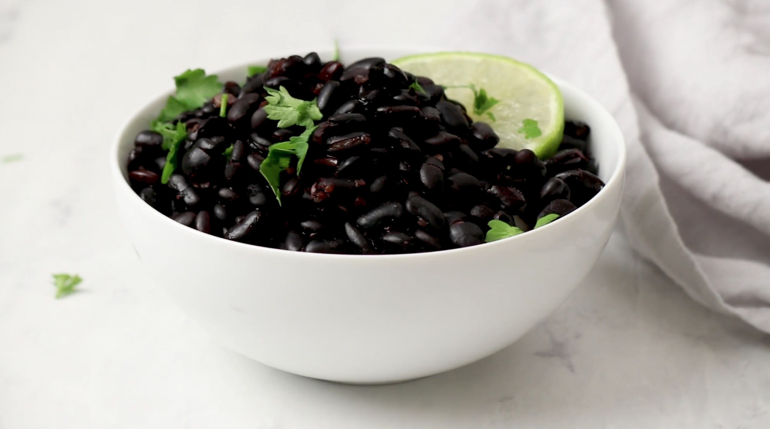 a bowl of black beans topped with cilantro and a lime wedge