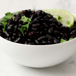 a bowl of black beans topped with cilantro and a lime wedge