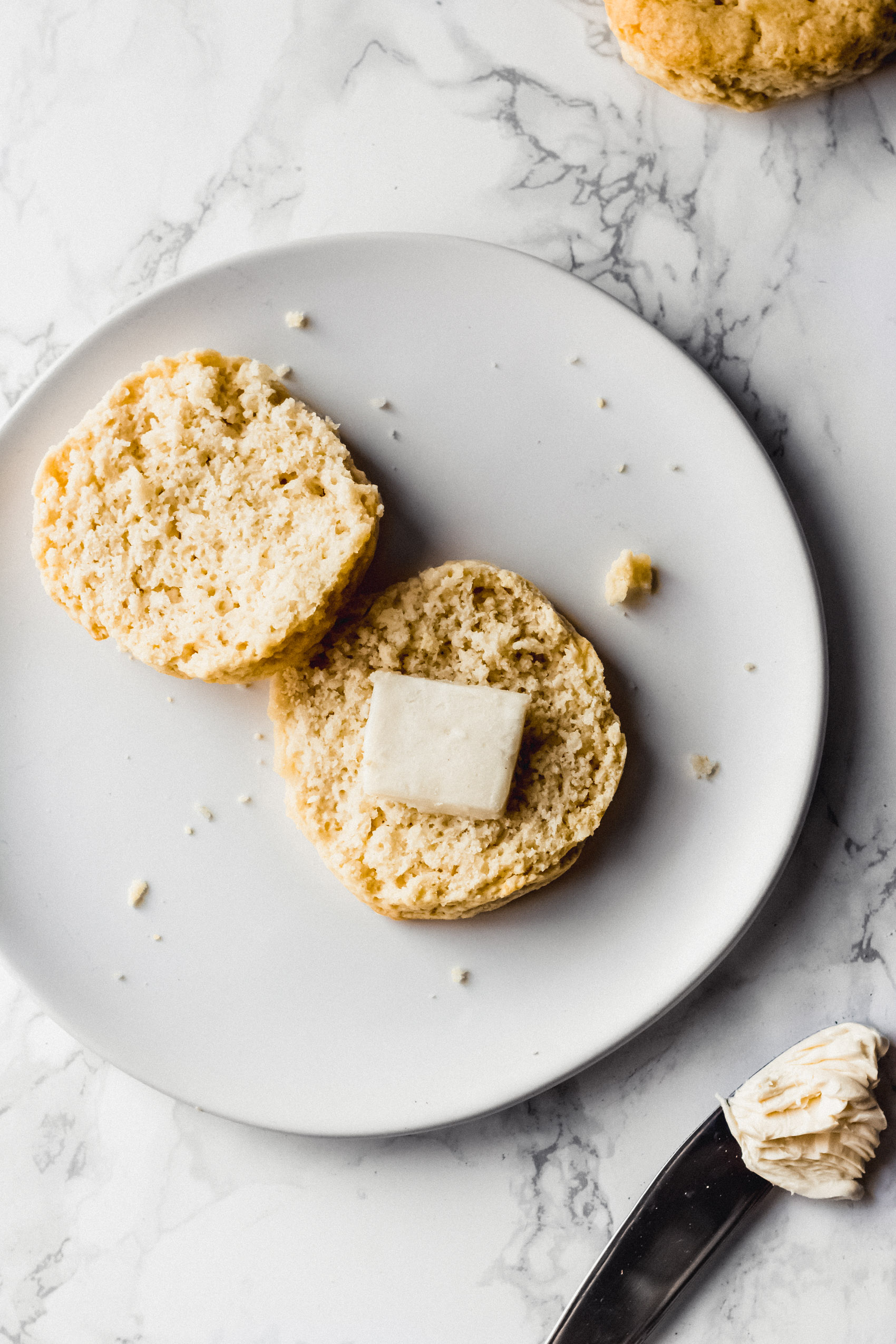 a biscuit sliced down the middle and topped with a slice of butter