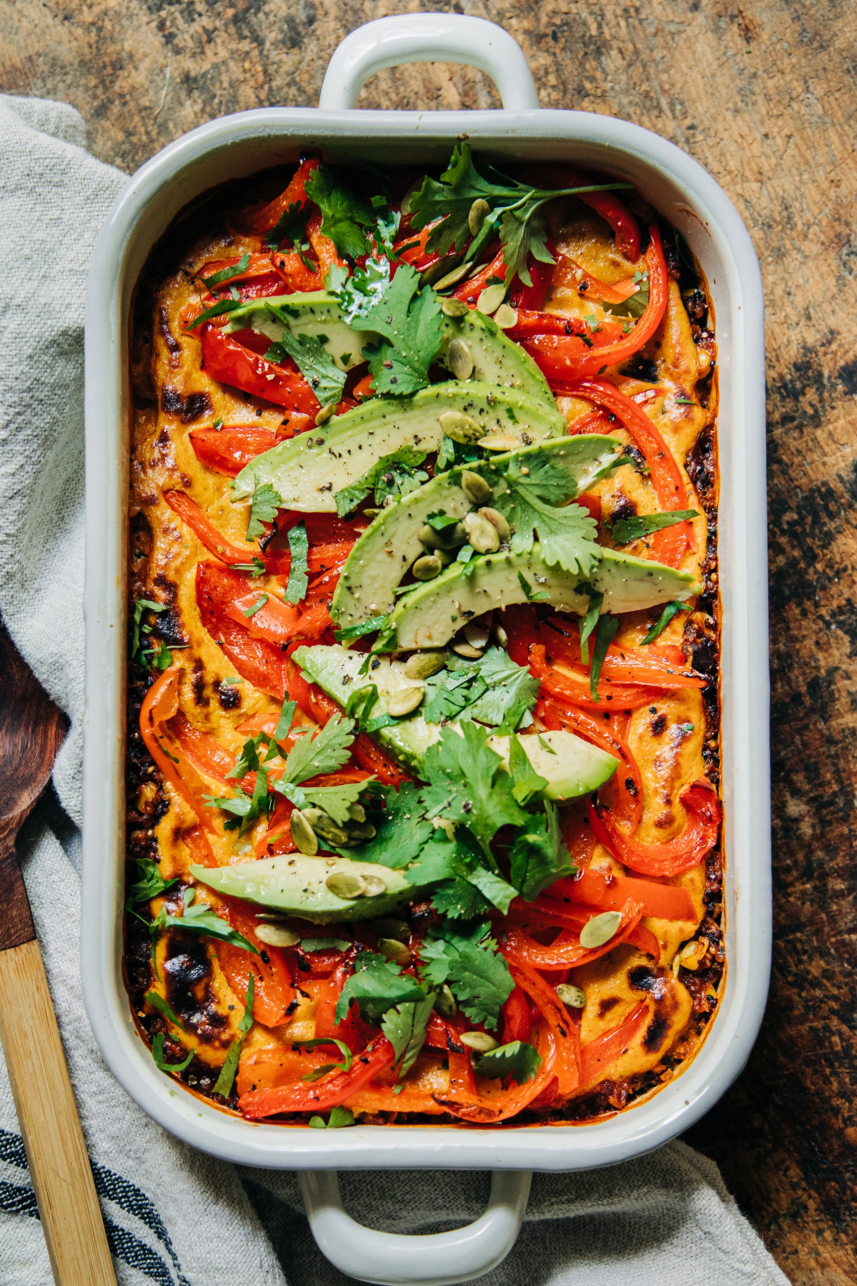 a vegan stuffed red pepper casserole topped with sliced avocado