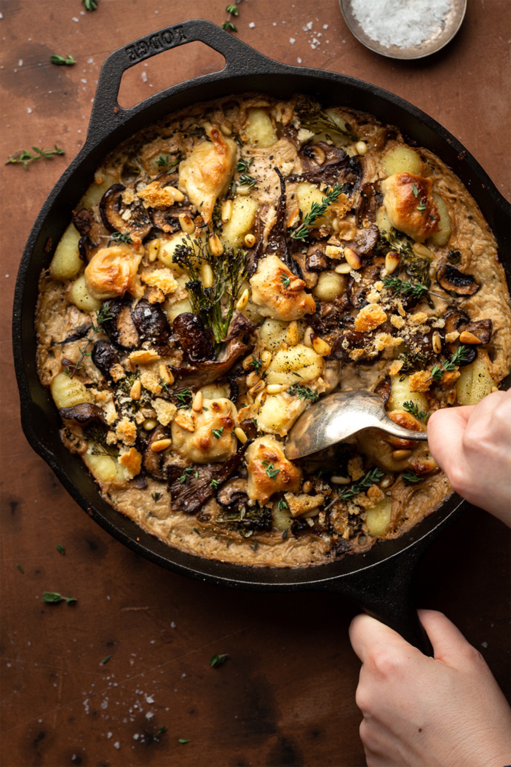 a spoon taking a scoop of a vegan mushroom gnocchi bake