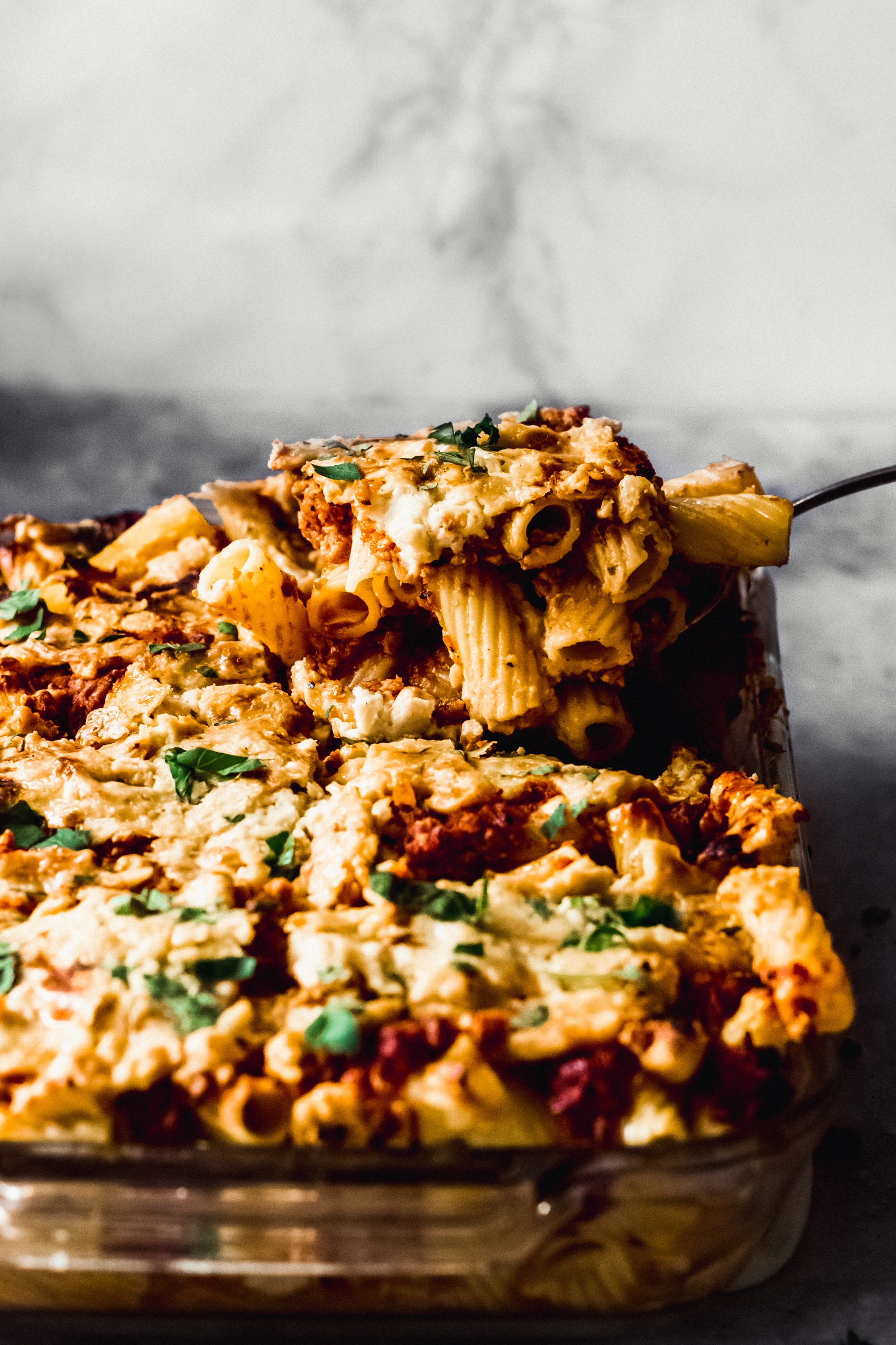 a spoon carving out a scoop of baked ziti