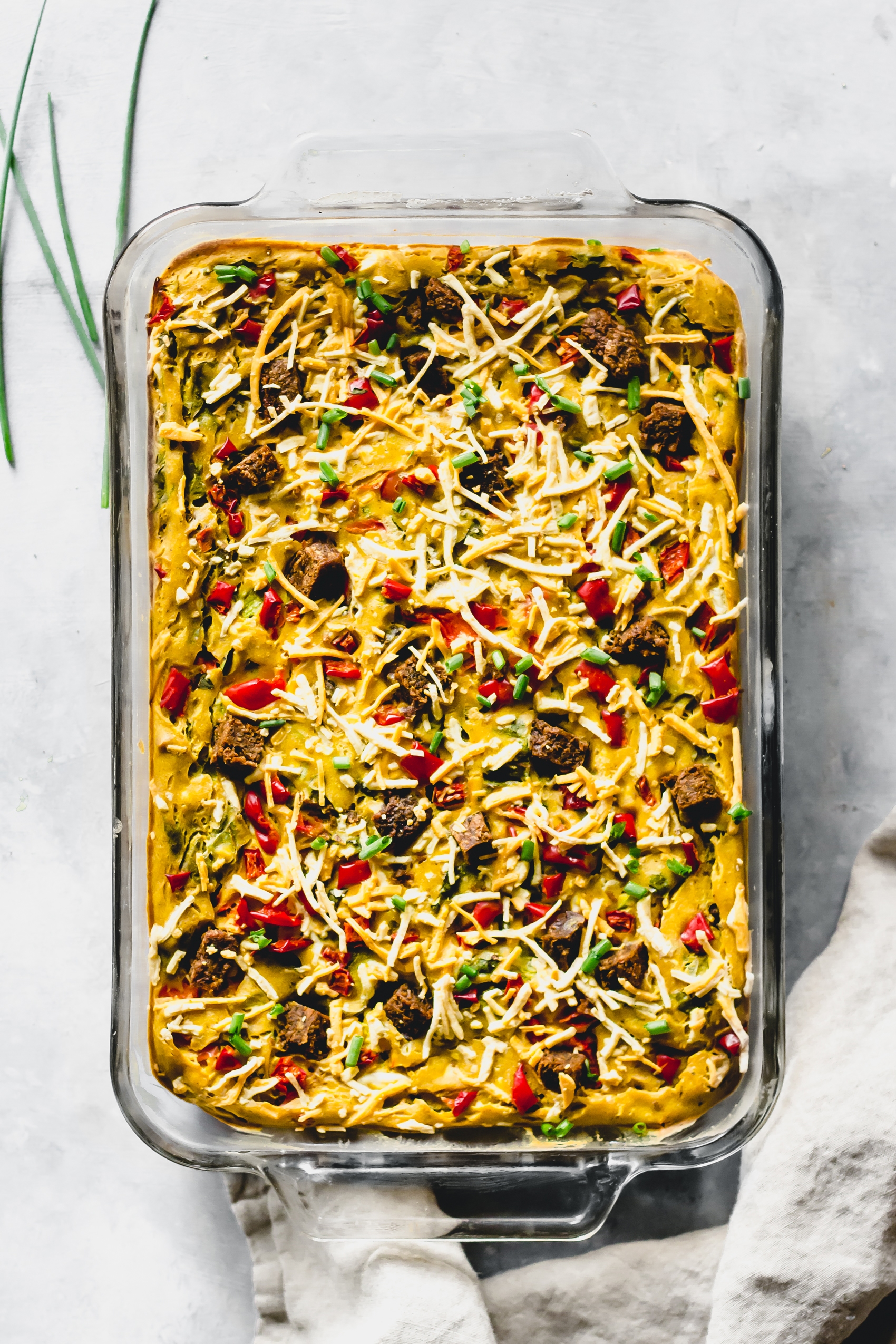 a casserole dish filled with a vegan egg casserole topped with shredded vegan cheese