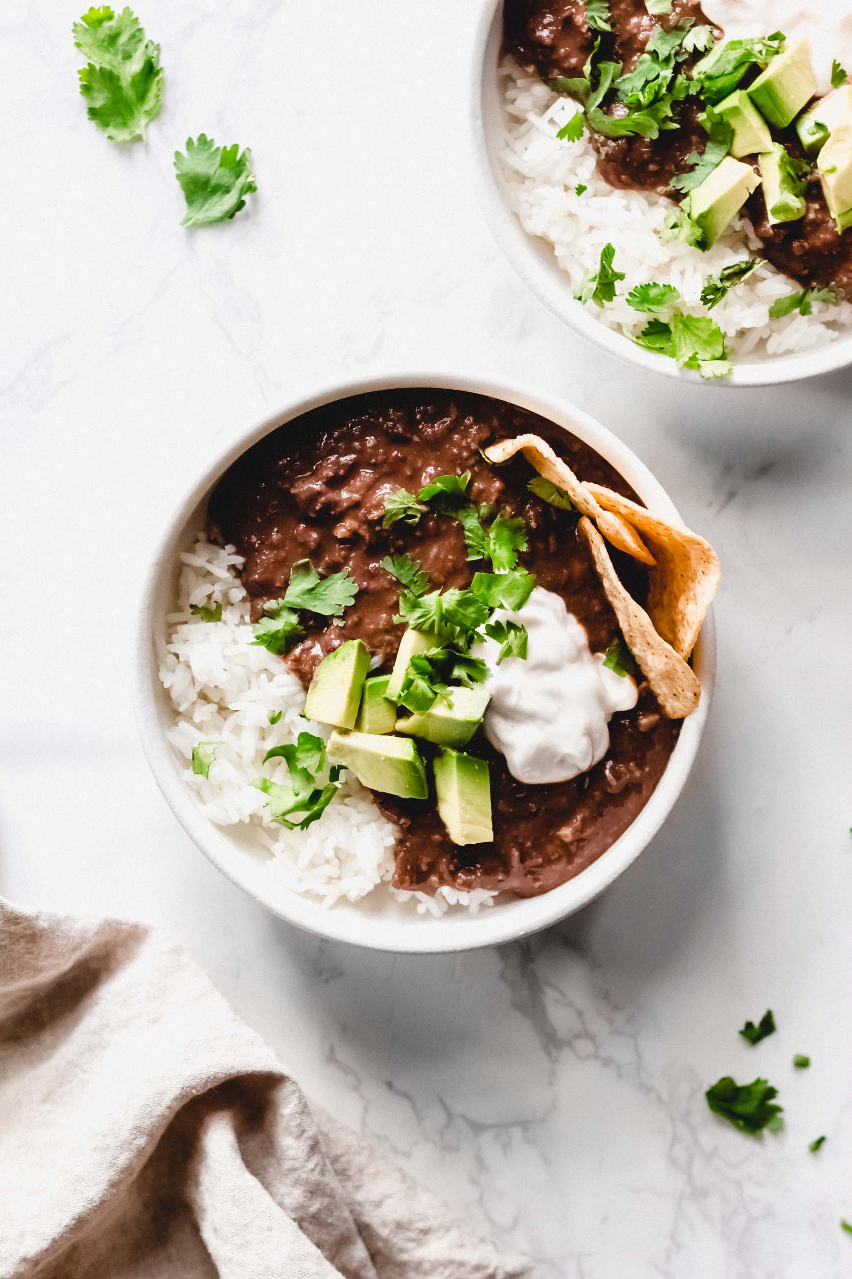 a bowl of vegan black bean soup topped with avocado, cilantro and sour cream