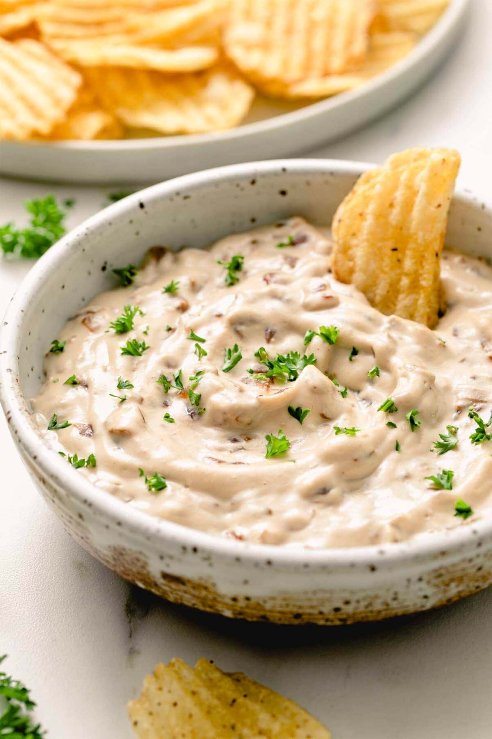 a chip being dipped into a vegan onion dip