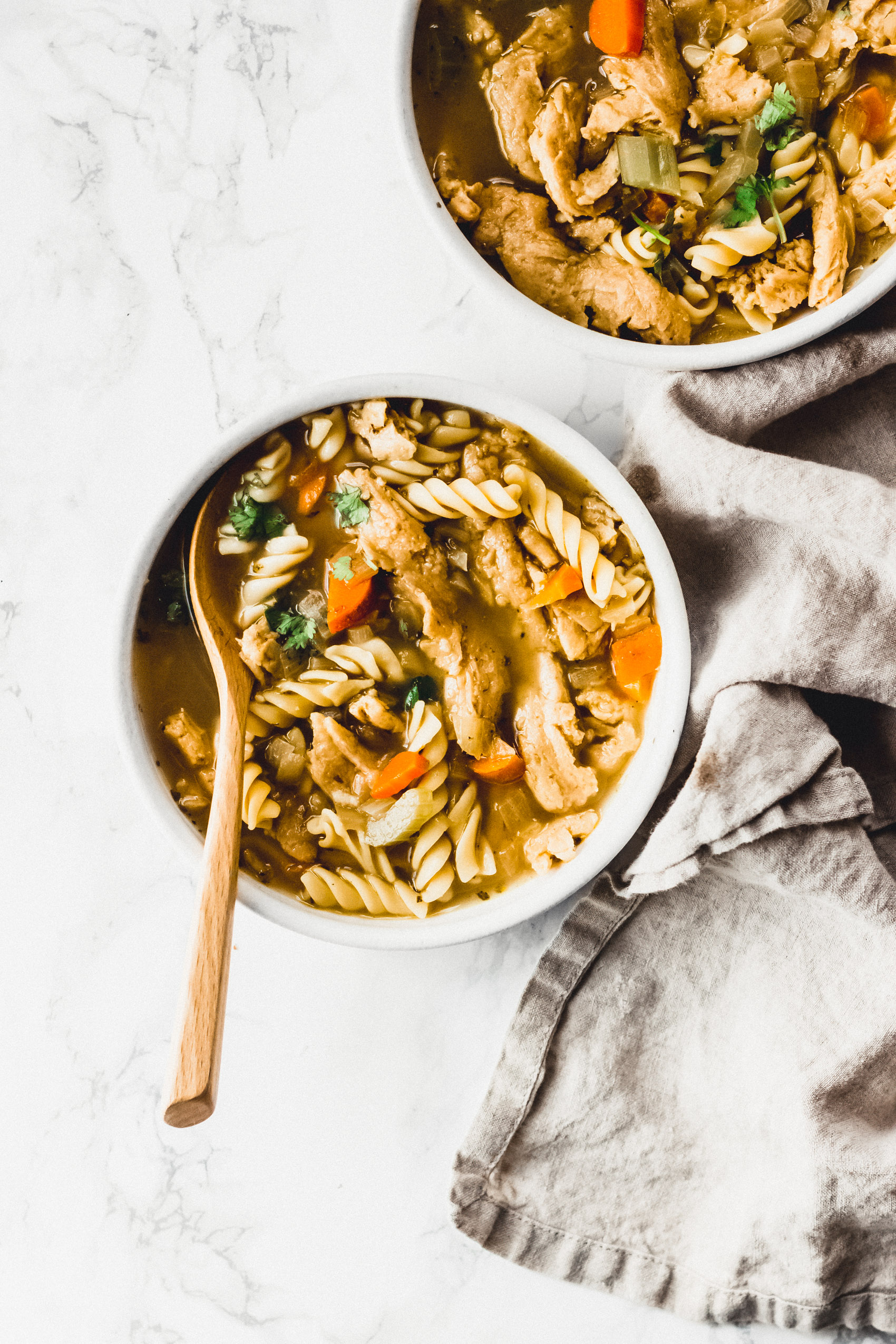 a spoon scooping into a bowl of vegan chicken noodle soup