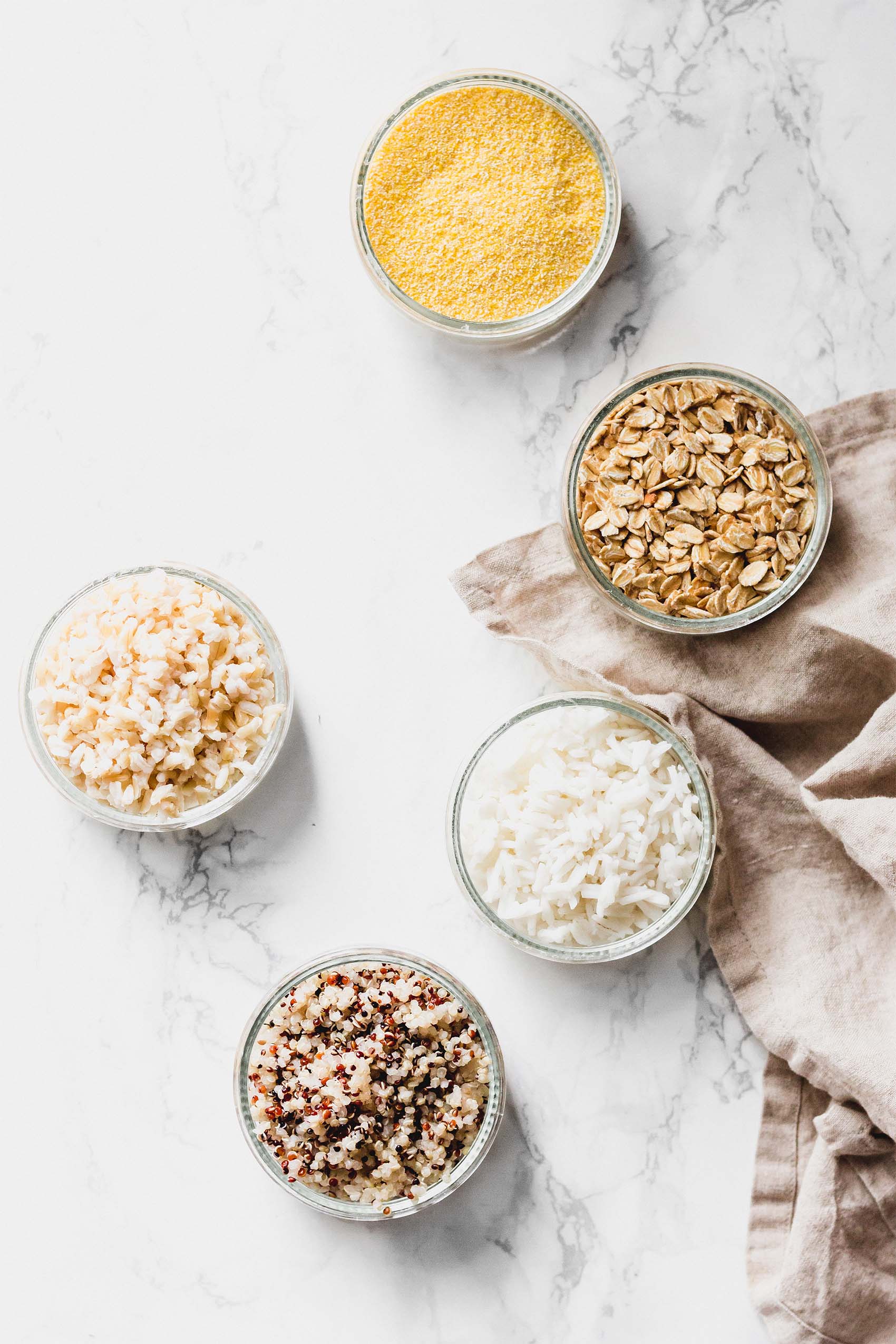 a collection of bowls of grains such as rice, quinoa and oats