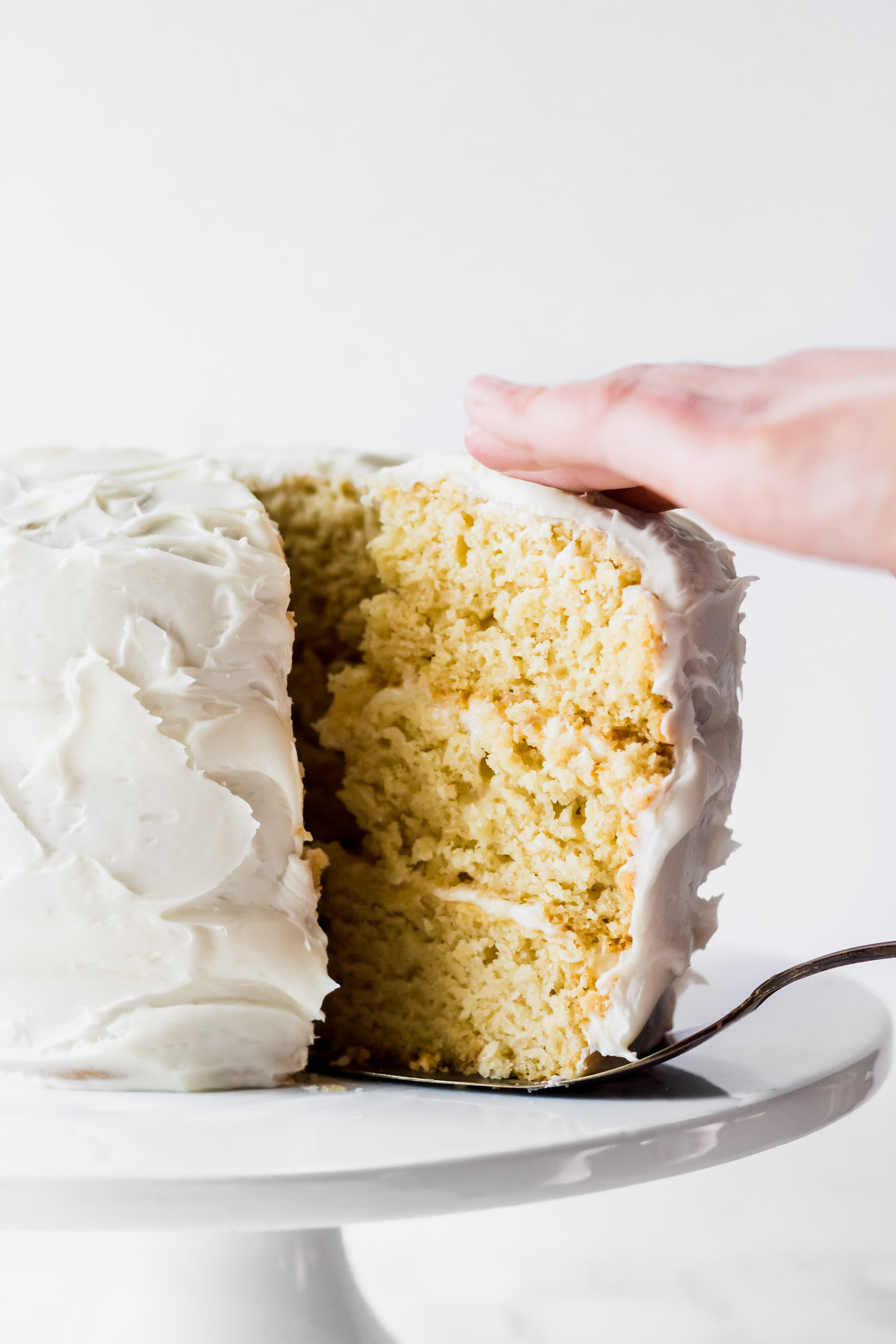 a slice of three-layer vanilla cake being sliced