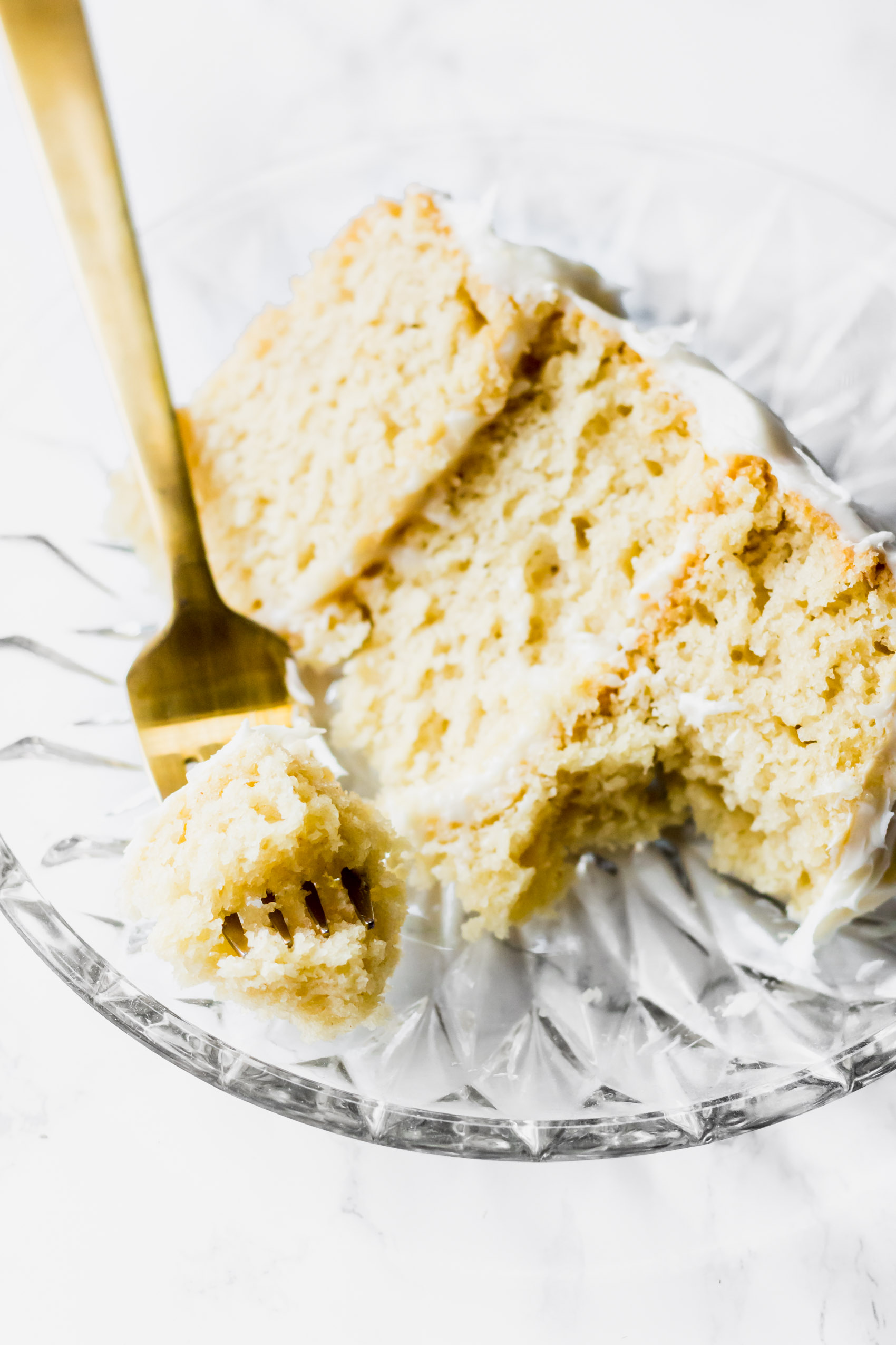 a fork taking a bite from a slice of vanilla cake