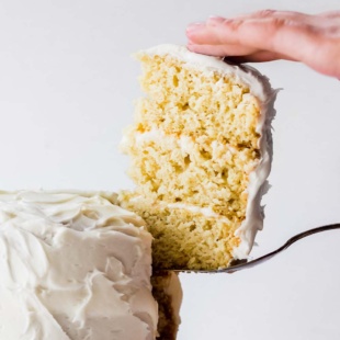 a slice of vanilla layer cake being removed from the whole cake
