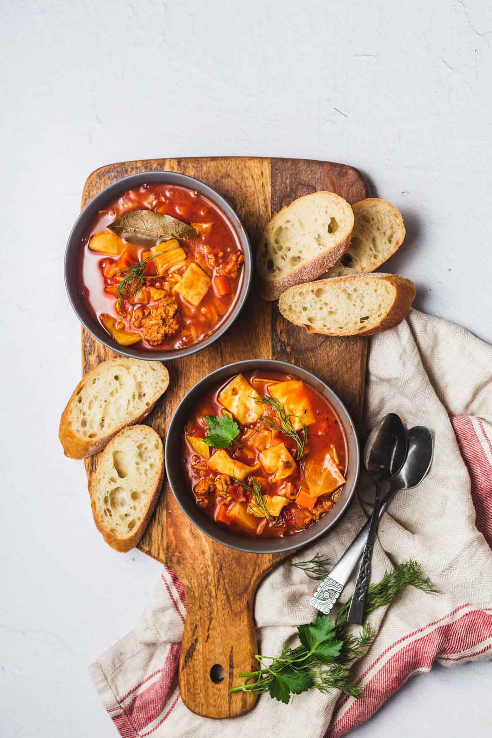 two bowls of cabbage roll soup served with sliced bread