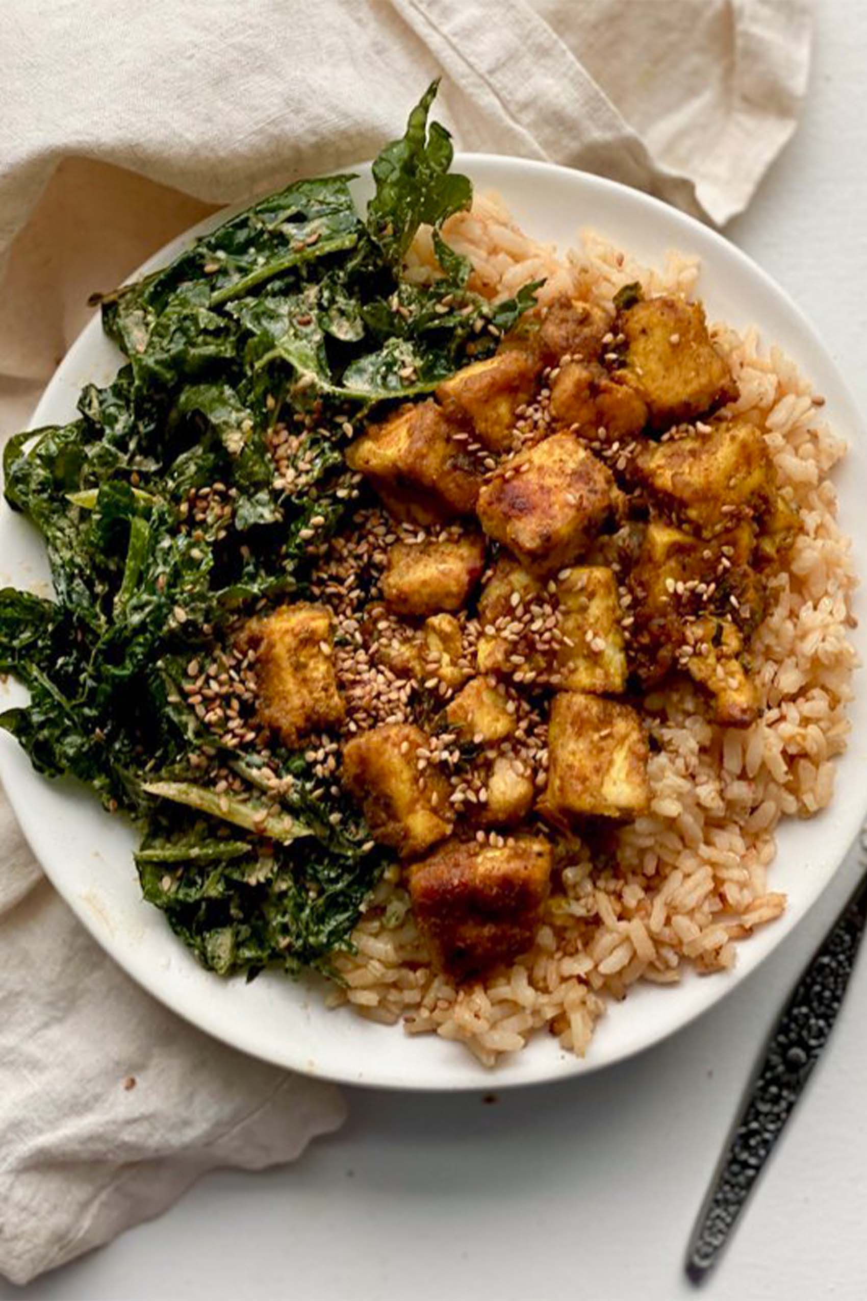 a plate of crispy fried tofu served with rice and kale