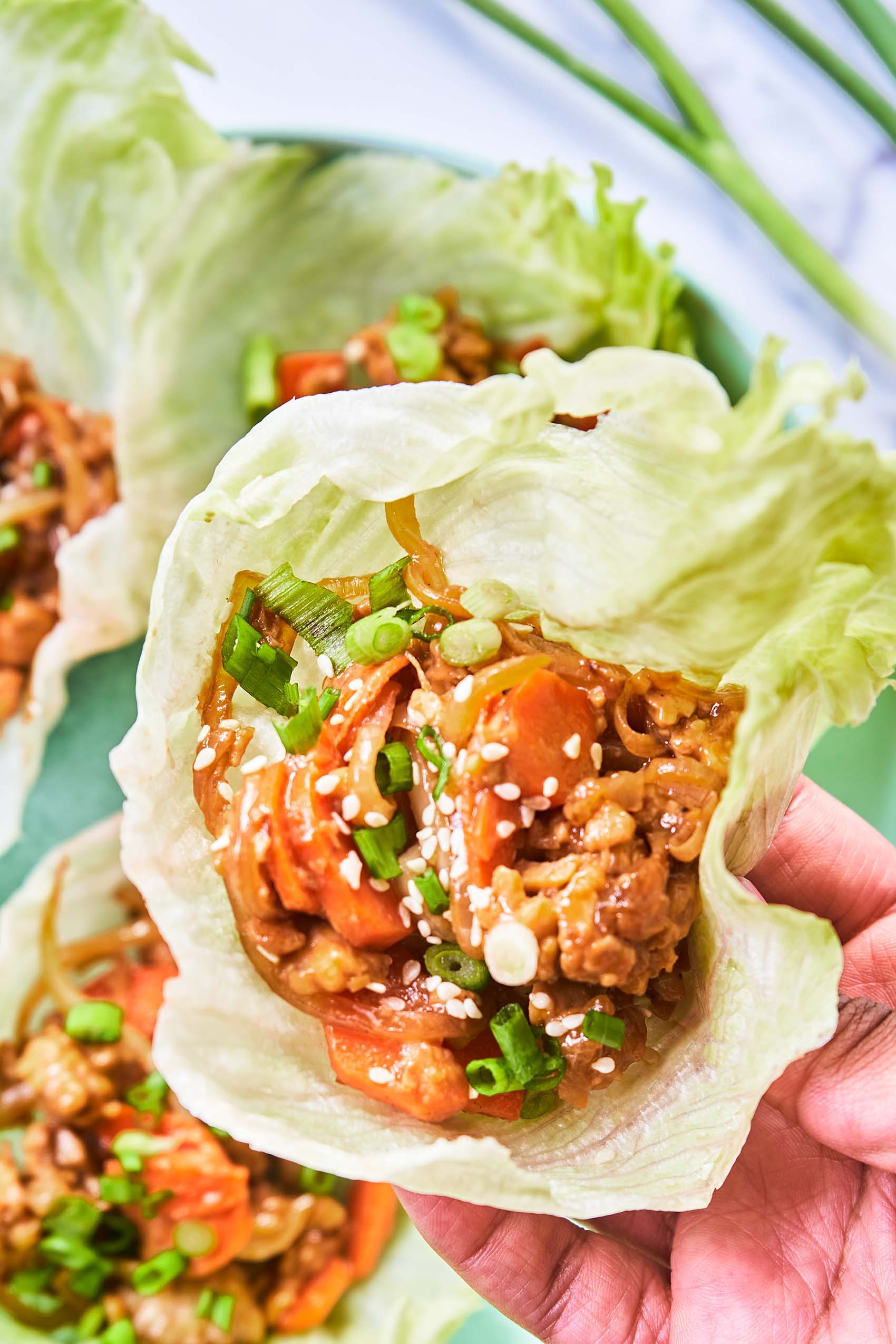 a hand holding a teriyaki tempeh lettuce wrap