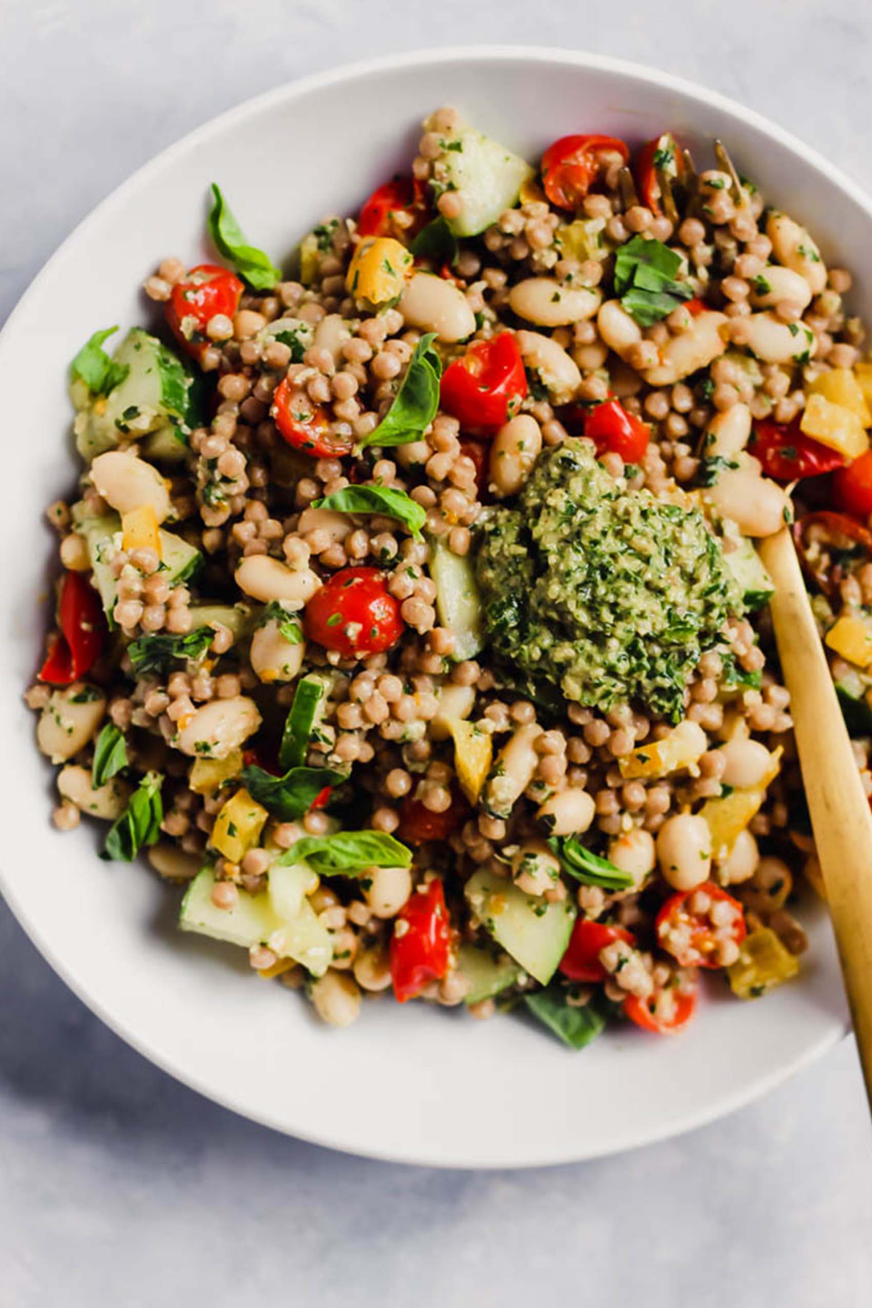 a bowl of couscous salad topped with pesto