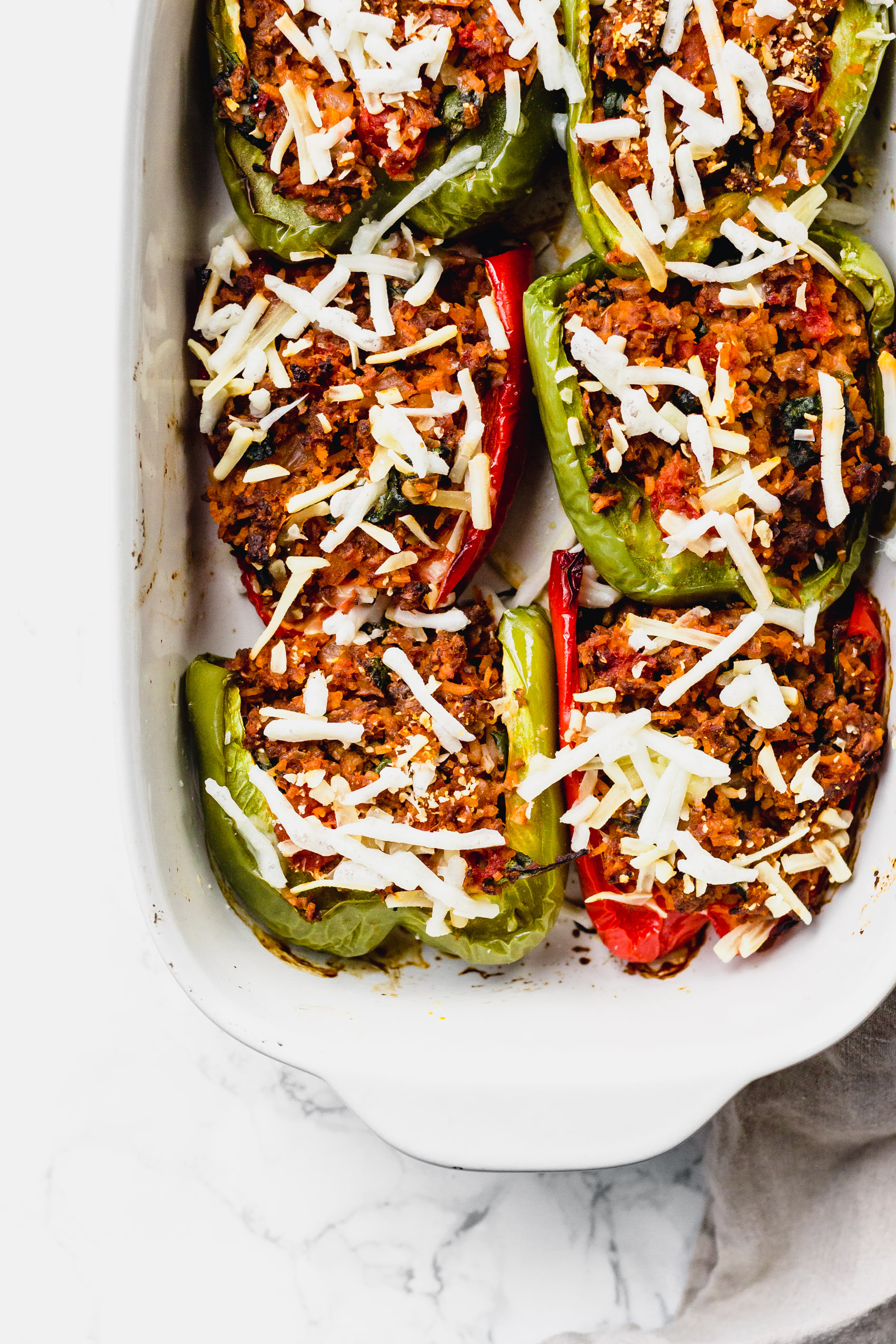 a casserole dish of baked bell peppers stuffed with vegan meat and cheese