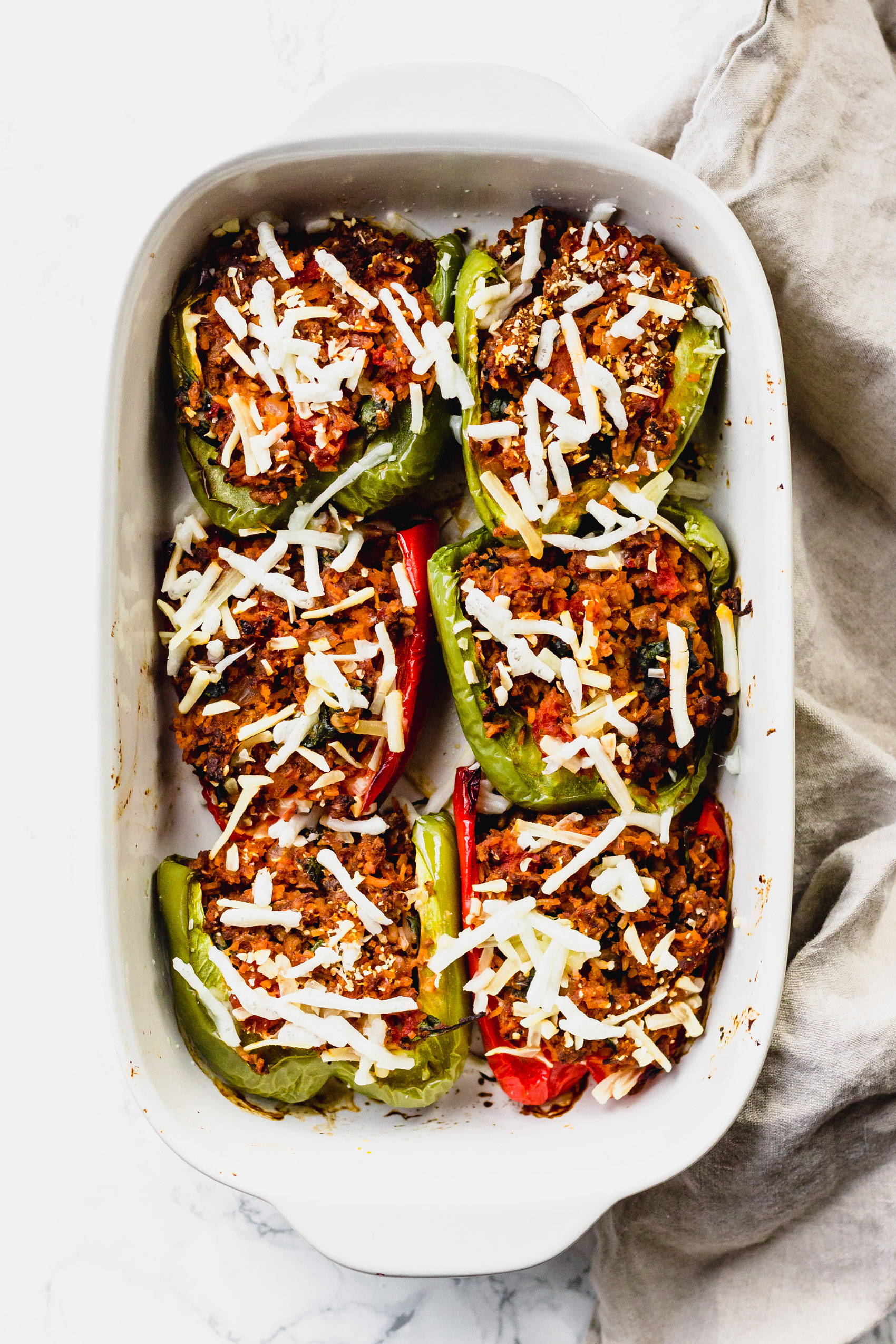 a dish full of six stuffed bell peppers topped with cheese