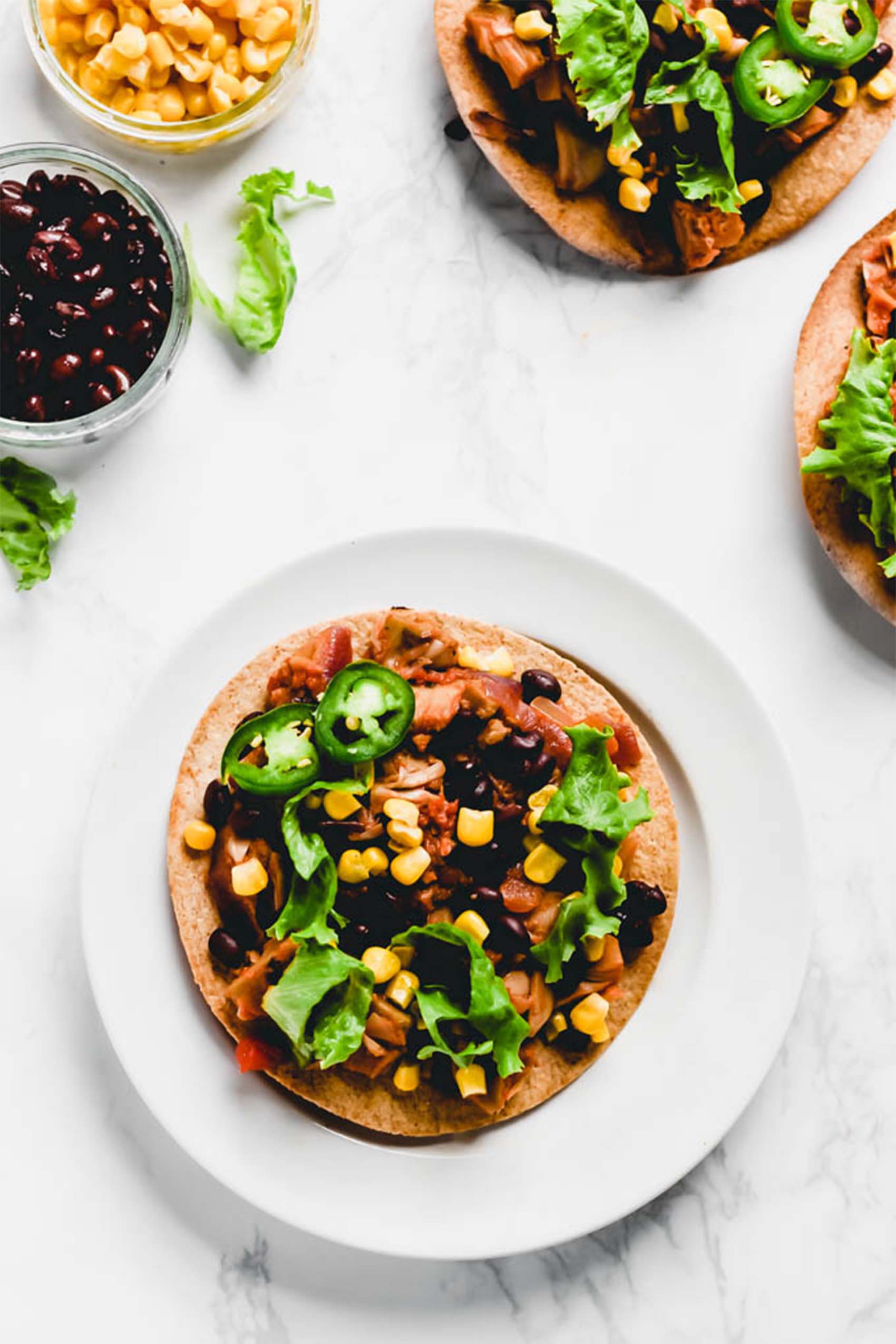 a black bean tostada topped with sliced jalapeno