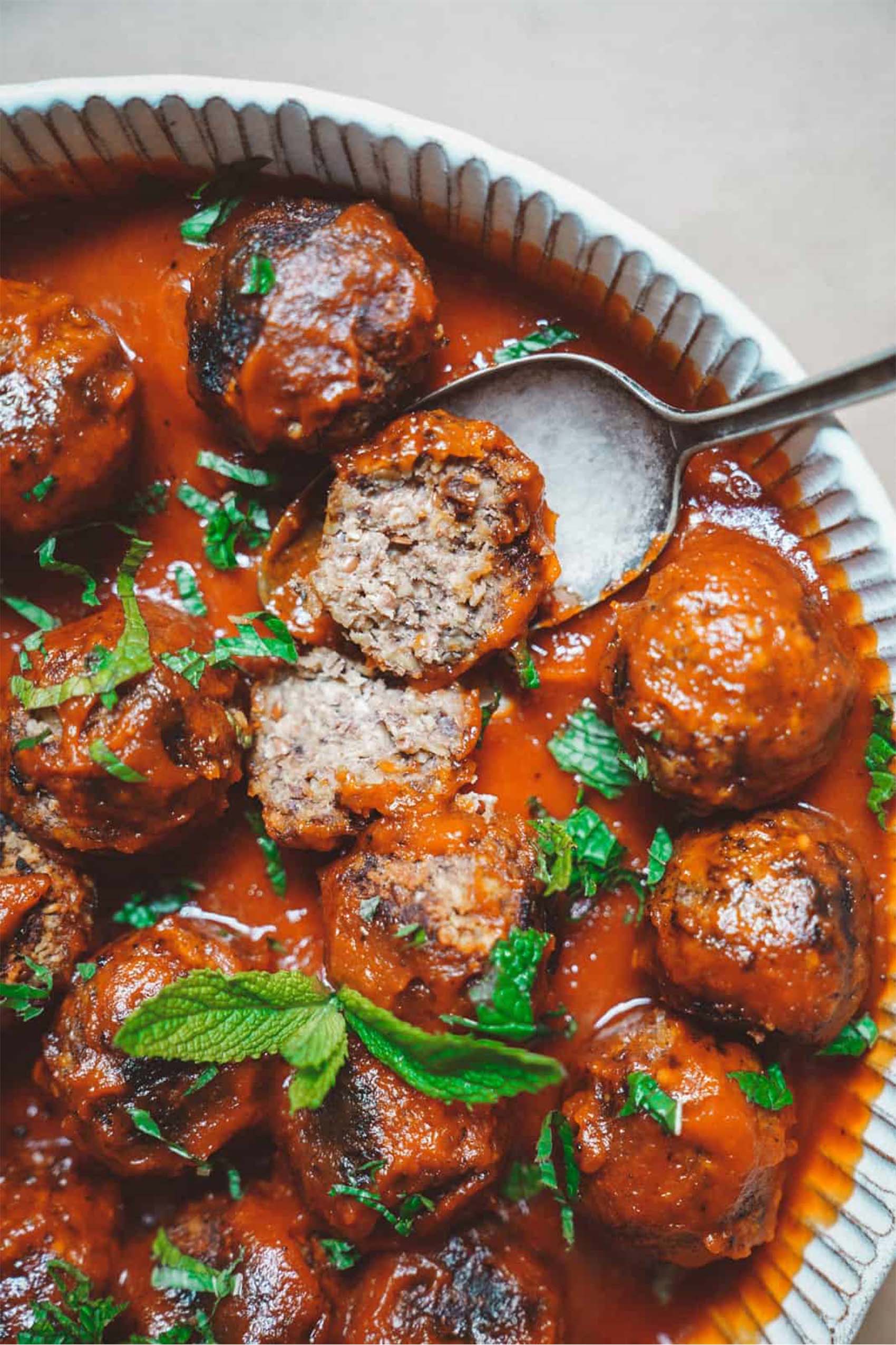 a platter of vegan meatballs served with marinara sauce and fresh basil