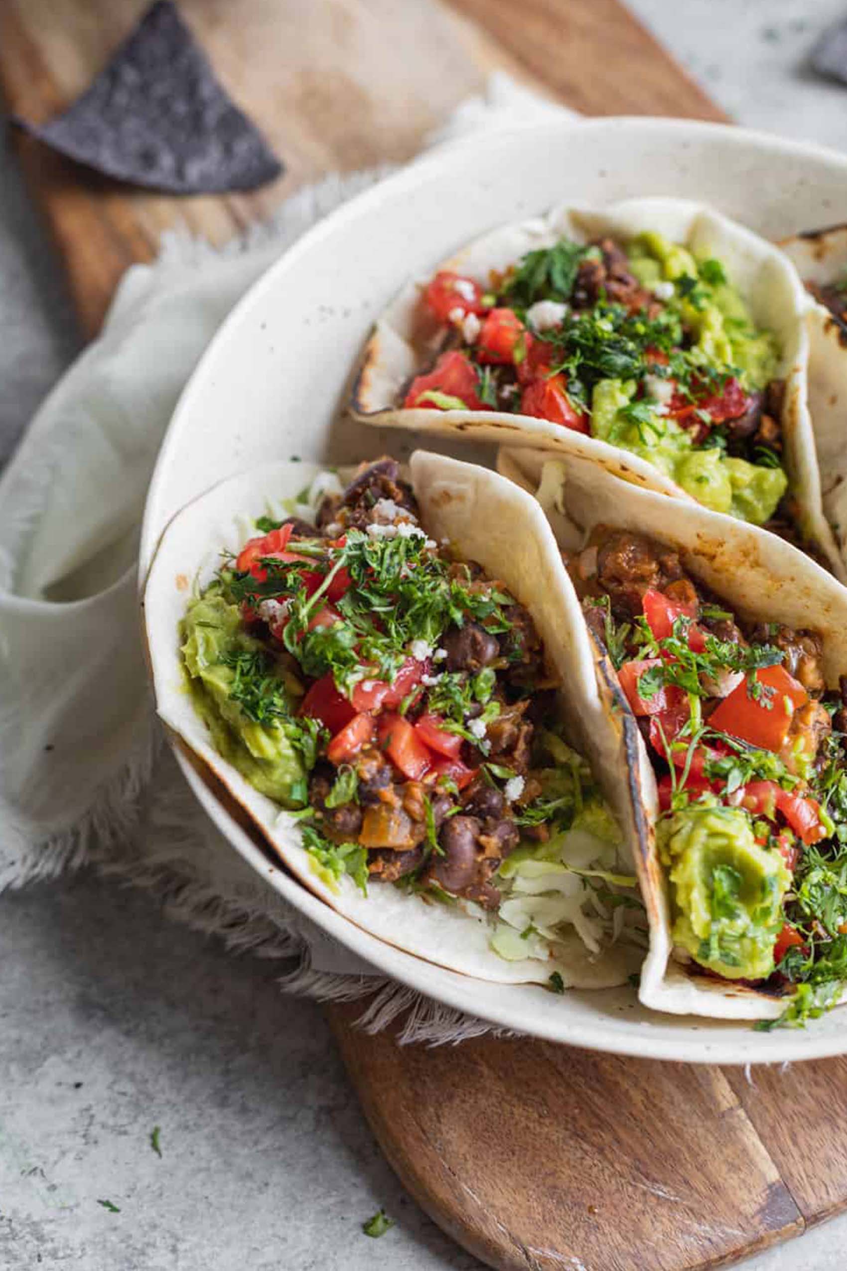 a platter of black bean tacos topped with guacamole