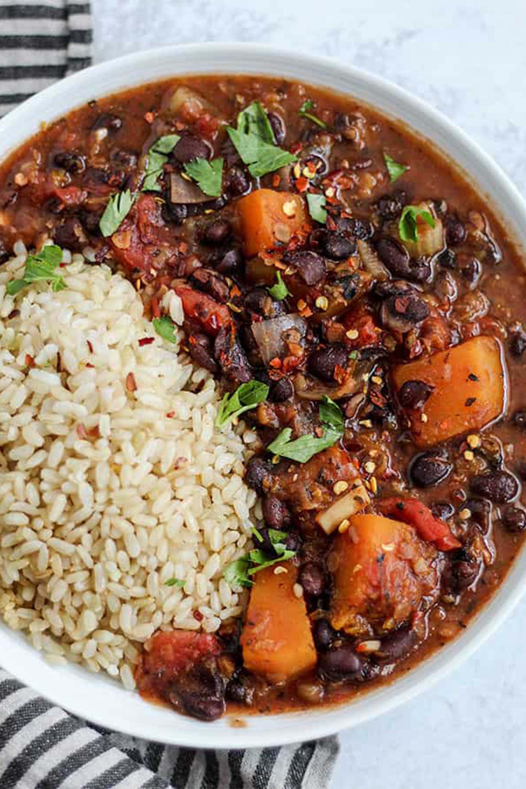 a bowl of black bean stew served with brown rice and topped with fresh cilantro