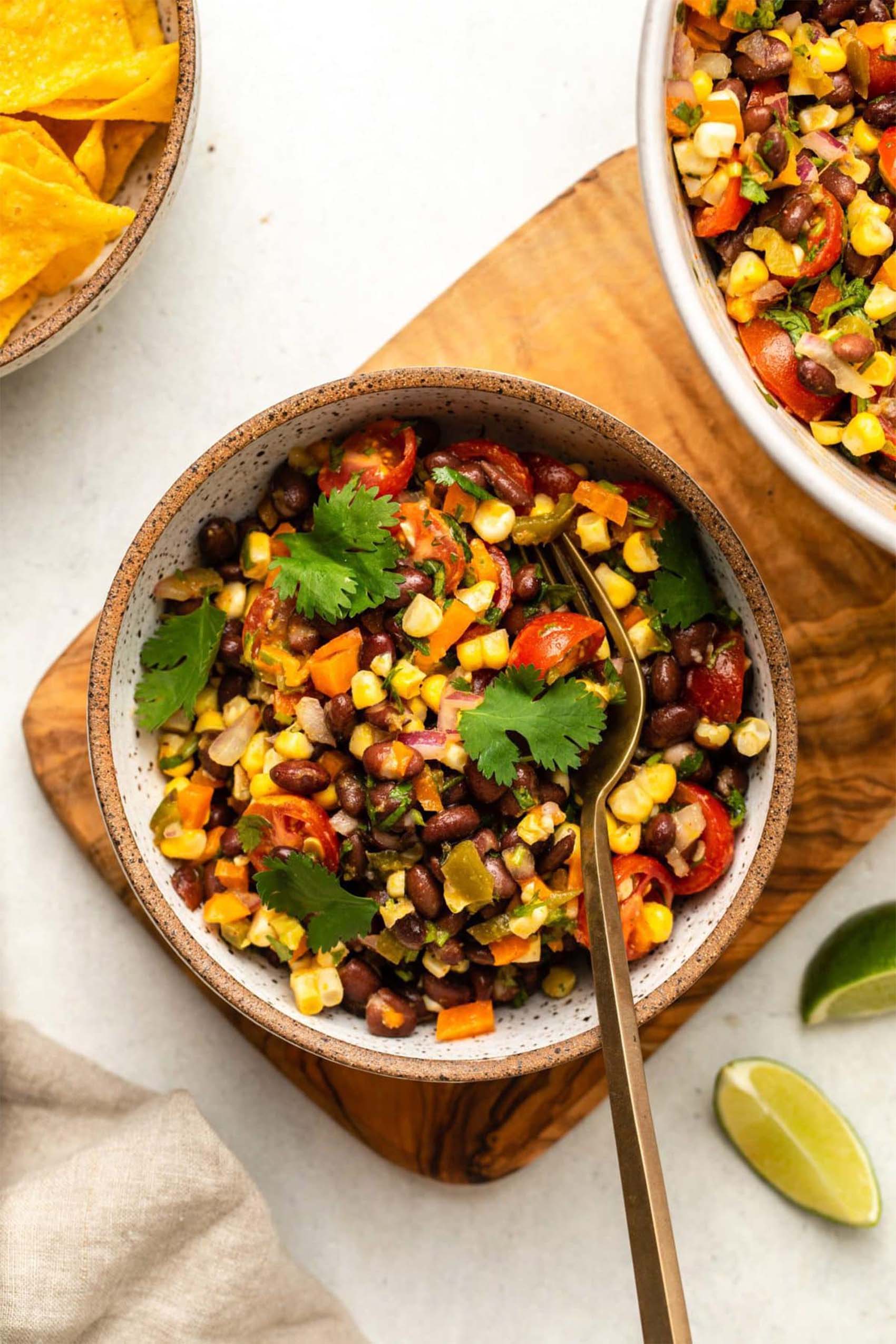 a bowl of corn, veggies and black beans topped with fresh herbs